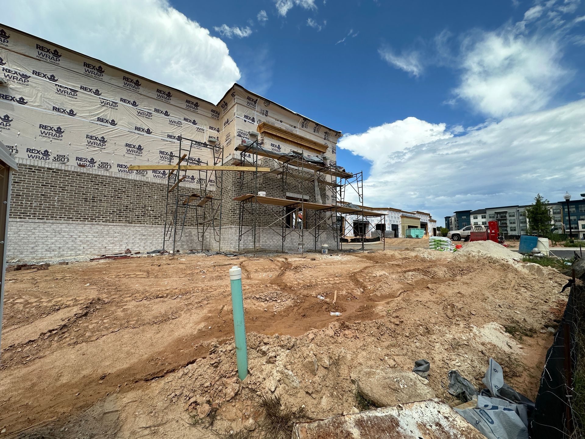 A large building is being built in the middle of a dirt field.