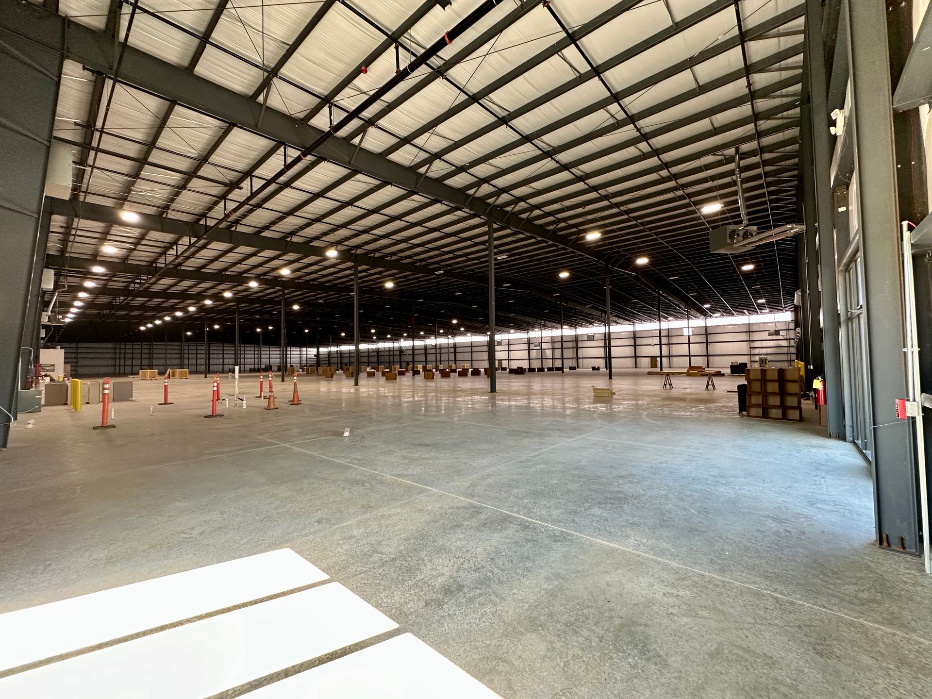A large empty warehouse with a lot of lights on the ceiling.
