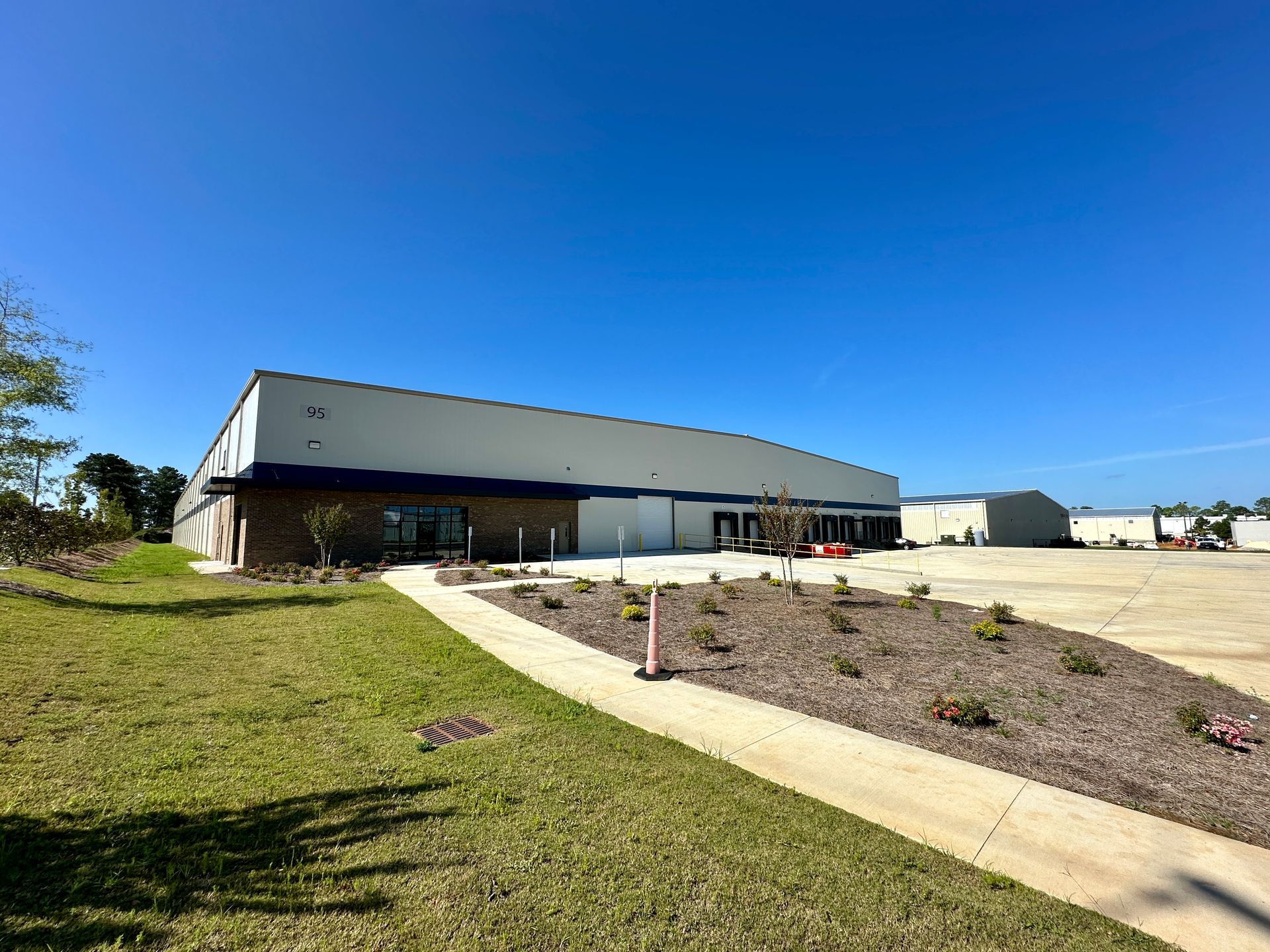 A large white building with a blue roof is sitting on top of a lush green field.