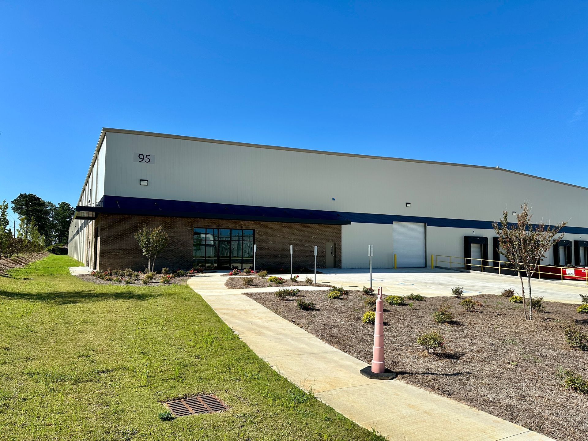 A large white building with a blue awning and a walkway leading to it.