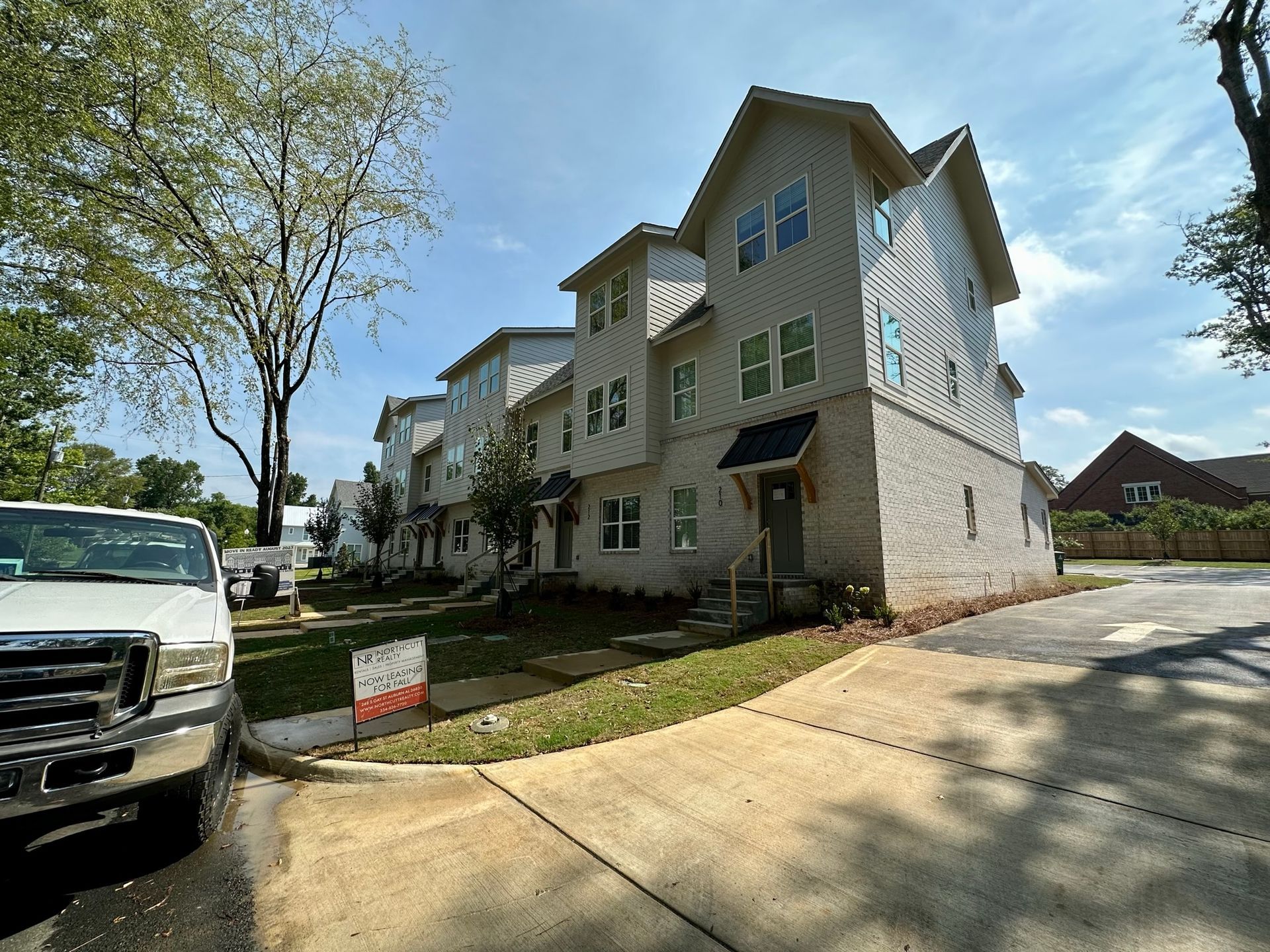 A white truck is parked in front of a large apartment building.