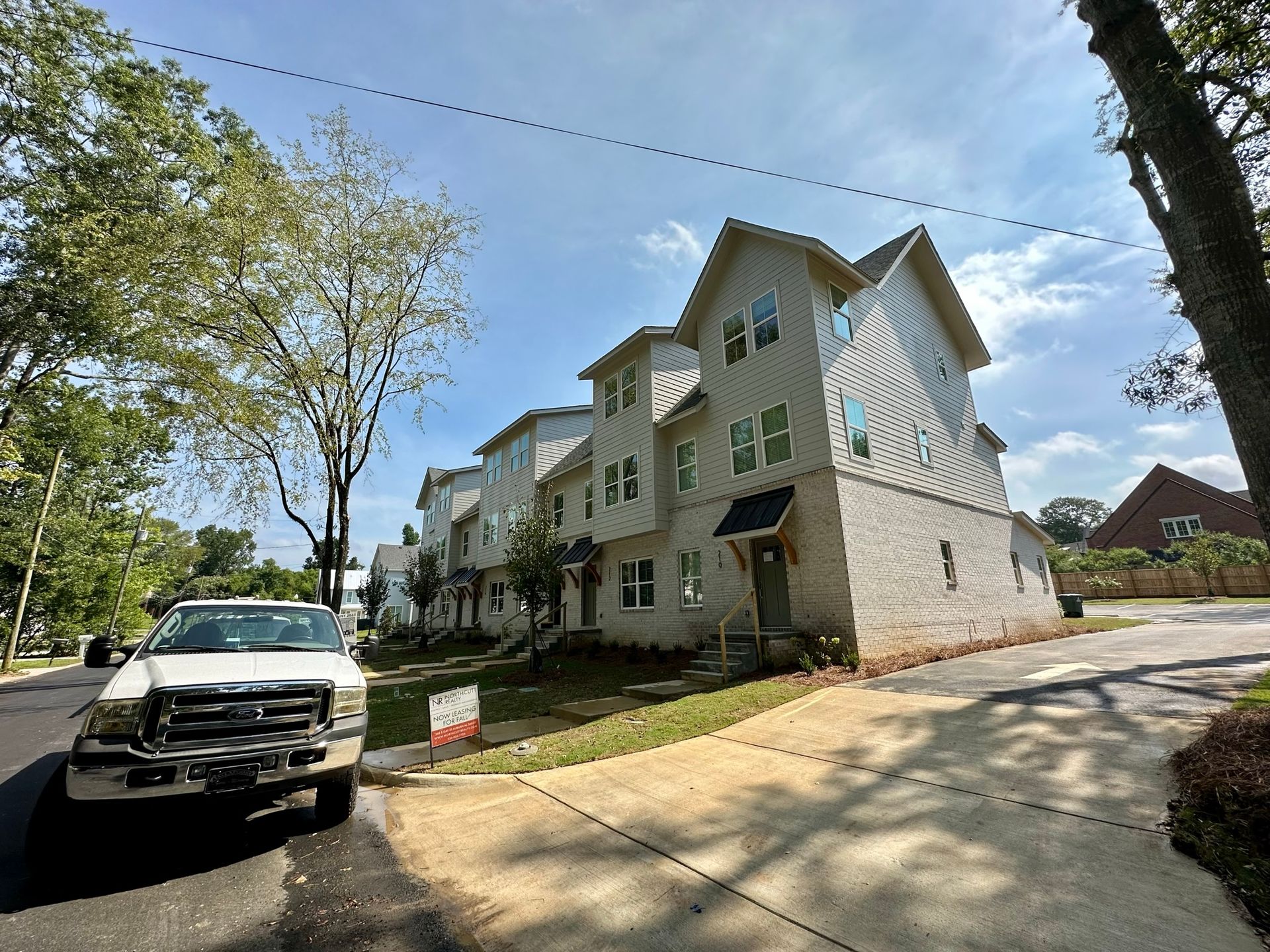 A white truck is parked in front of a large white building.