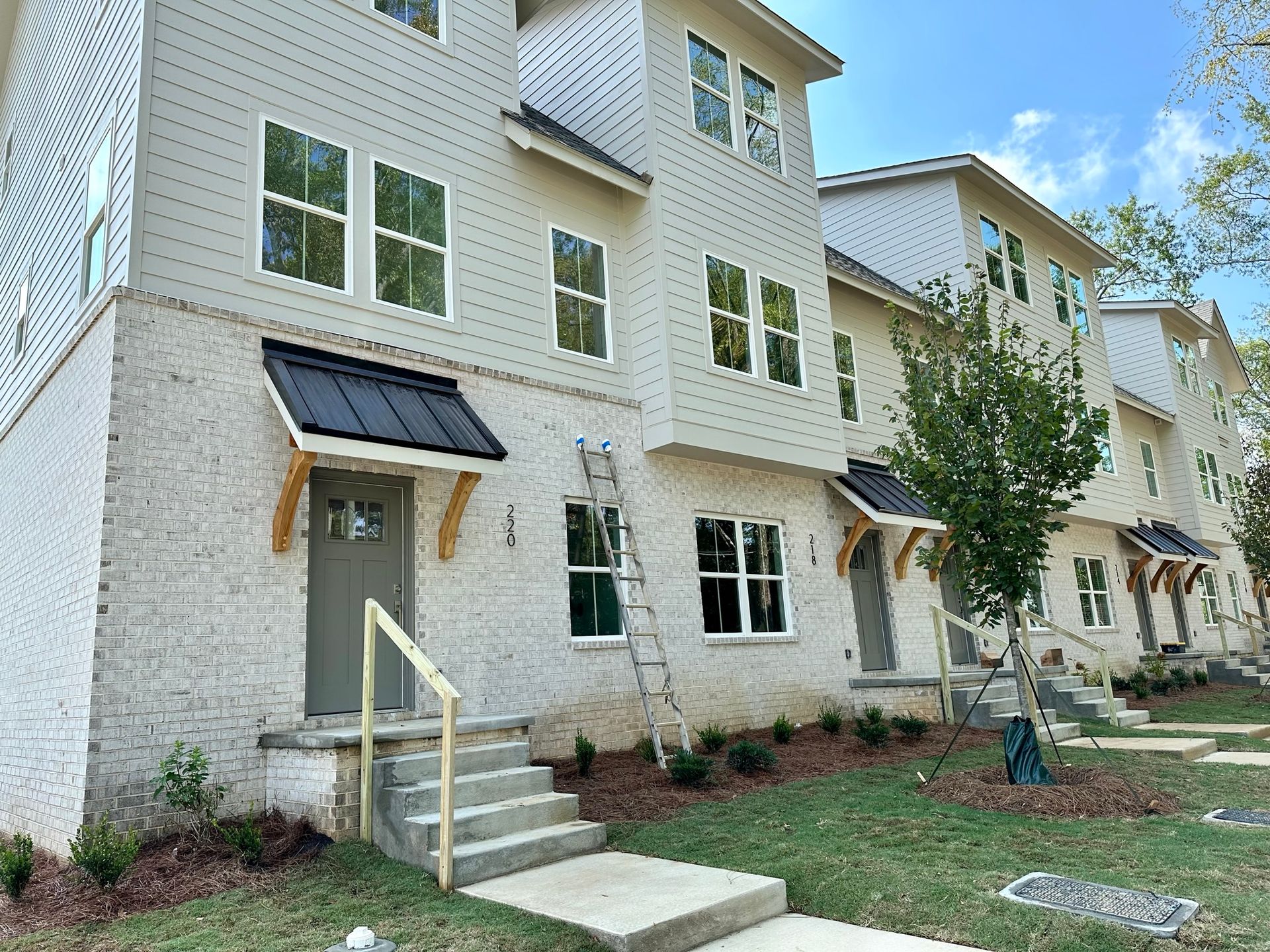 A white brick apartment building with a ladder in front of it.