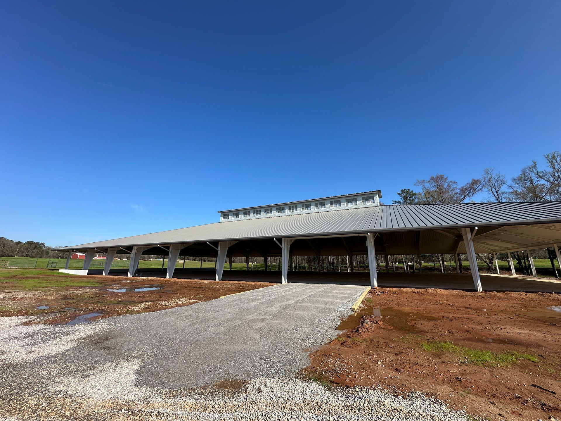An aerial view of a new Hovey Precast office building with a blue roof surrounded by trees.