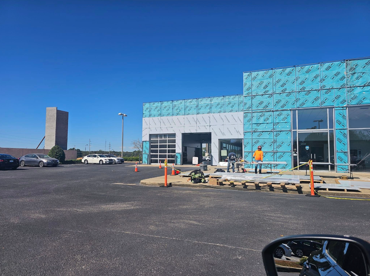 A car is parked in front of a building under construction.