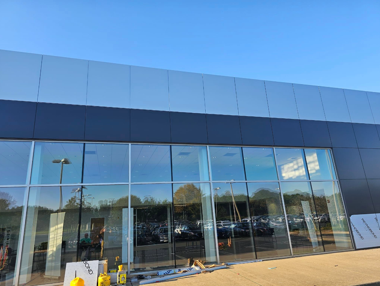 A large building with a lot of windows and a lot of cars parked in front of it.