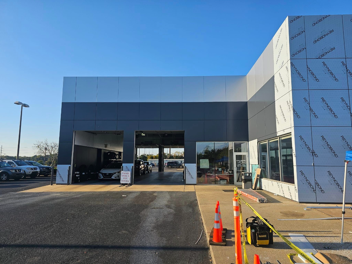 A car dealership under construction with a lot of cars parked in front of it.