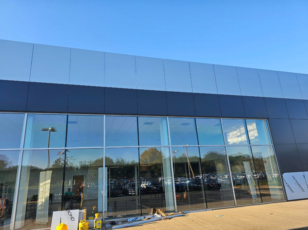A large building with a lot of windows and a lot of cars parked in front of it.