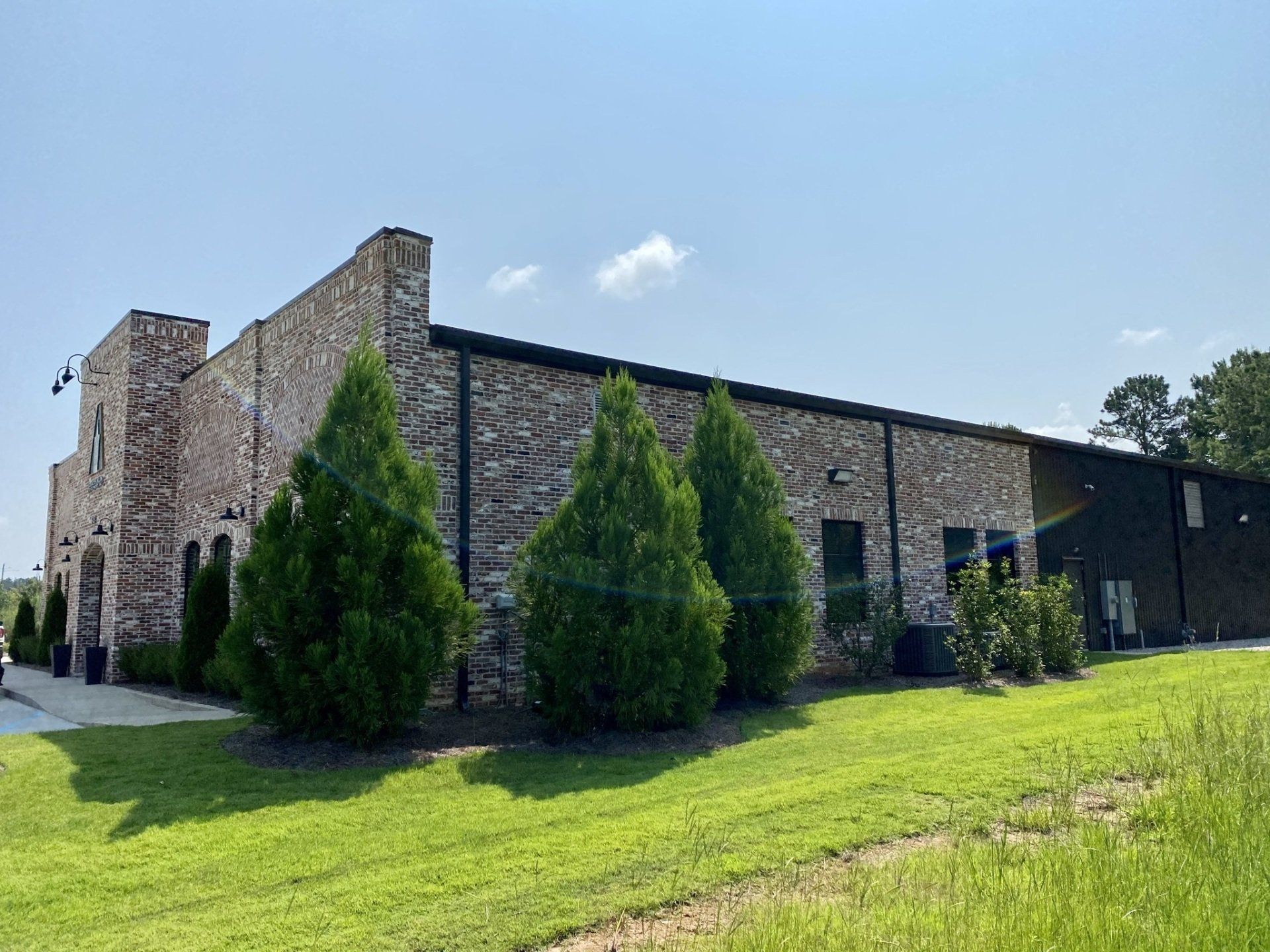 A large brick building with trees in front of it is sitting on top of a lush green field.