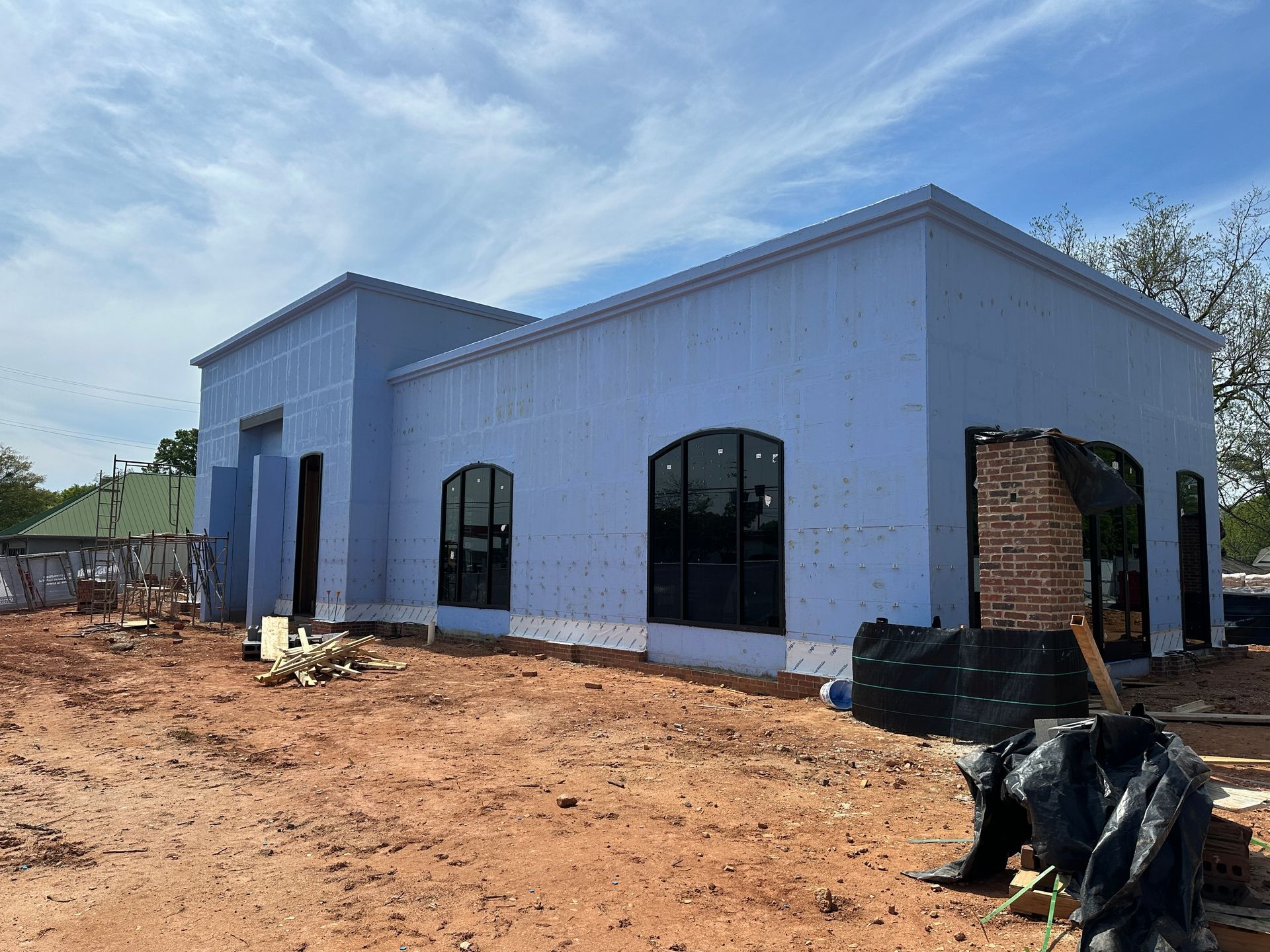 An aerial view of a new Hovey Precast office building with a blue roof surrounded by trees.
