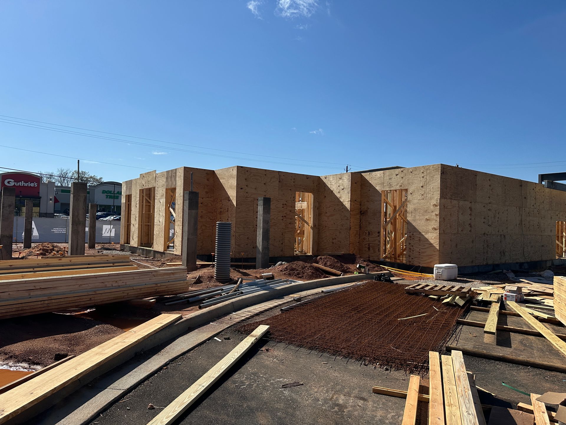 A wooden framing structure of a building under construction on a sunny day with a blue sky.