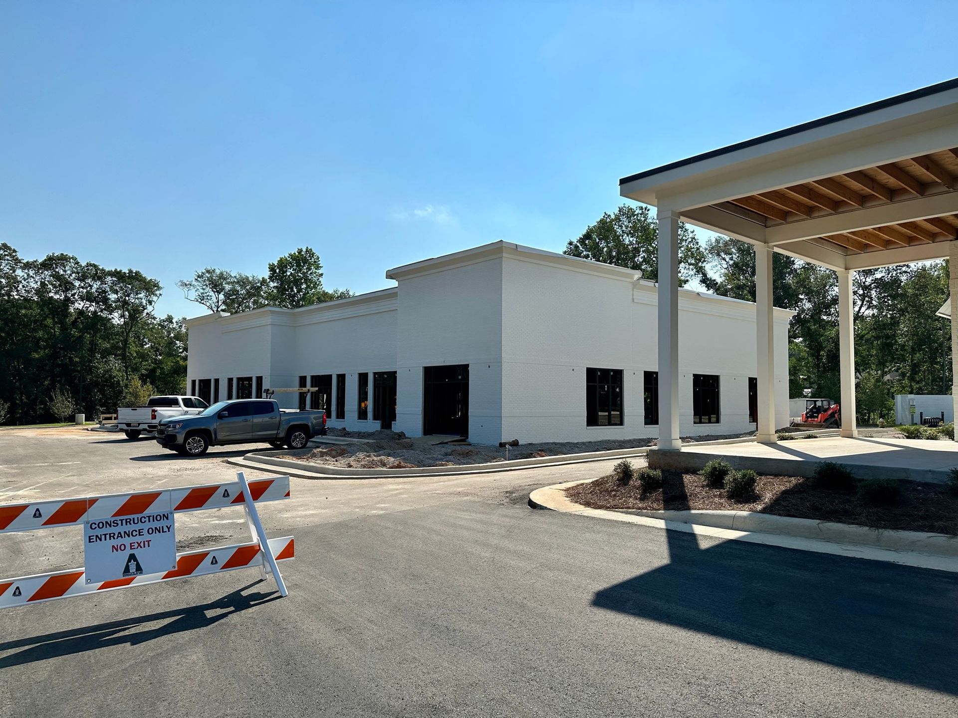 A white building is being built next to a road barrier.