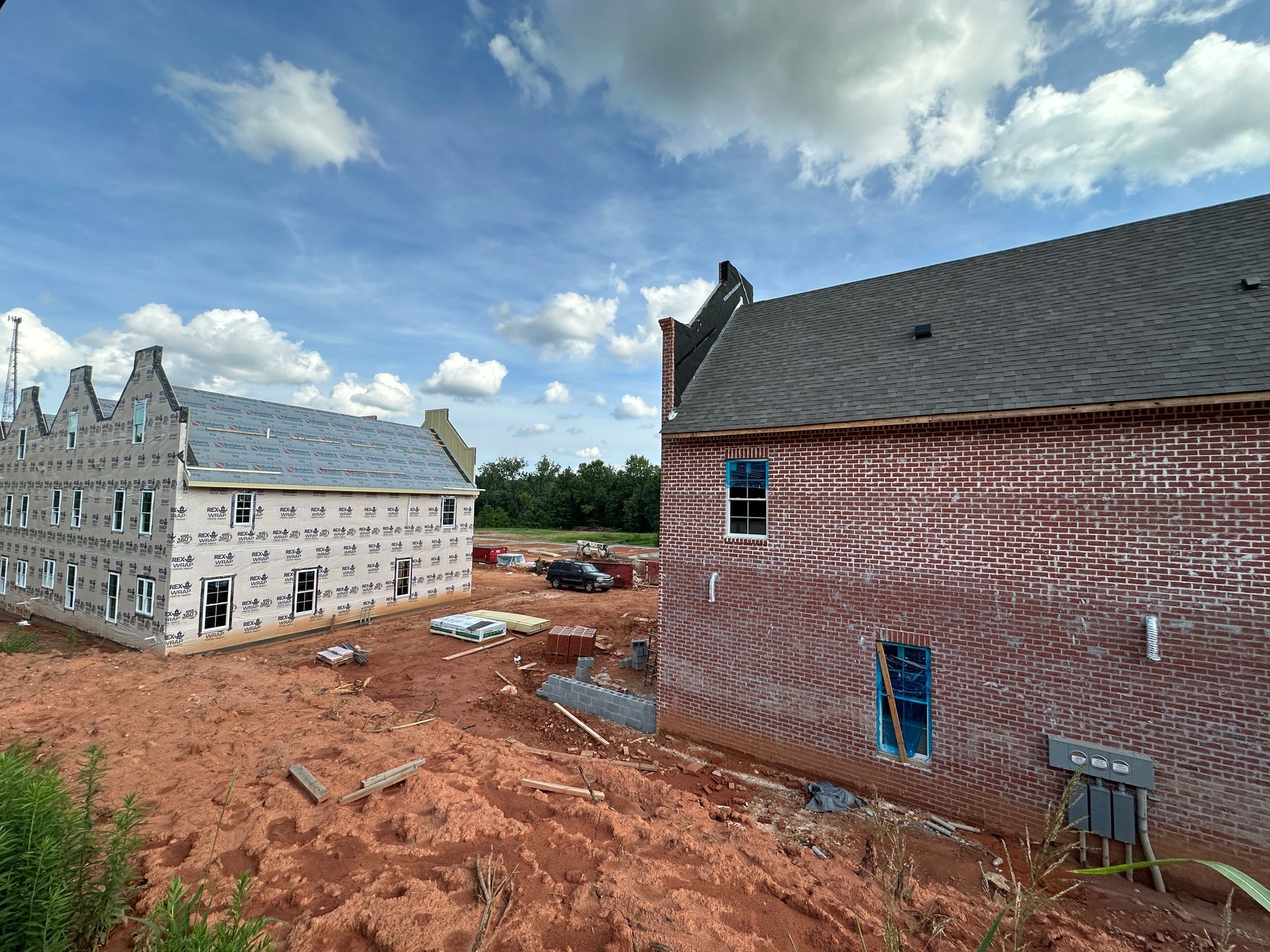 Two brick houses are being built on a dirt hill.