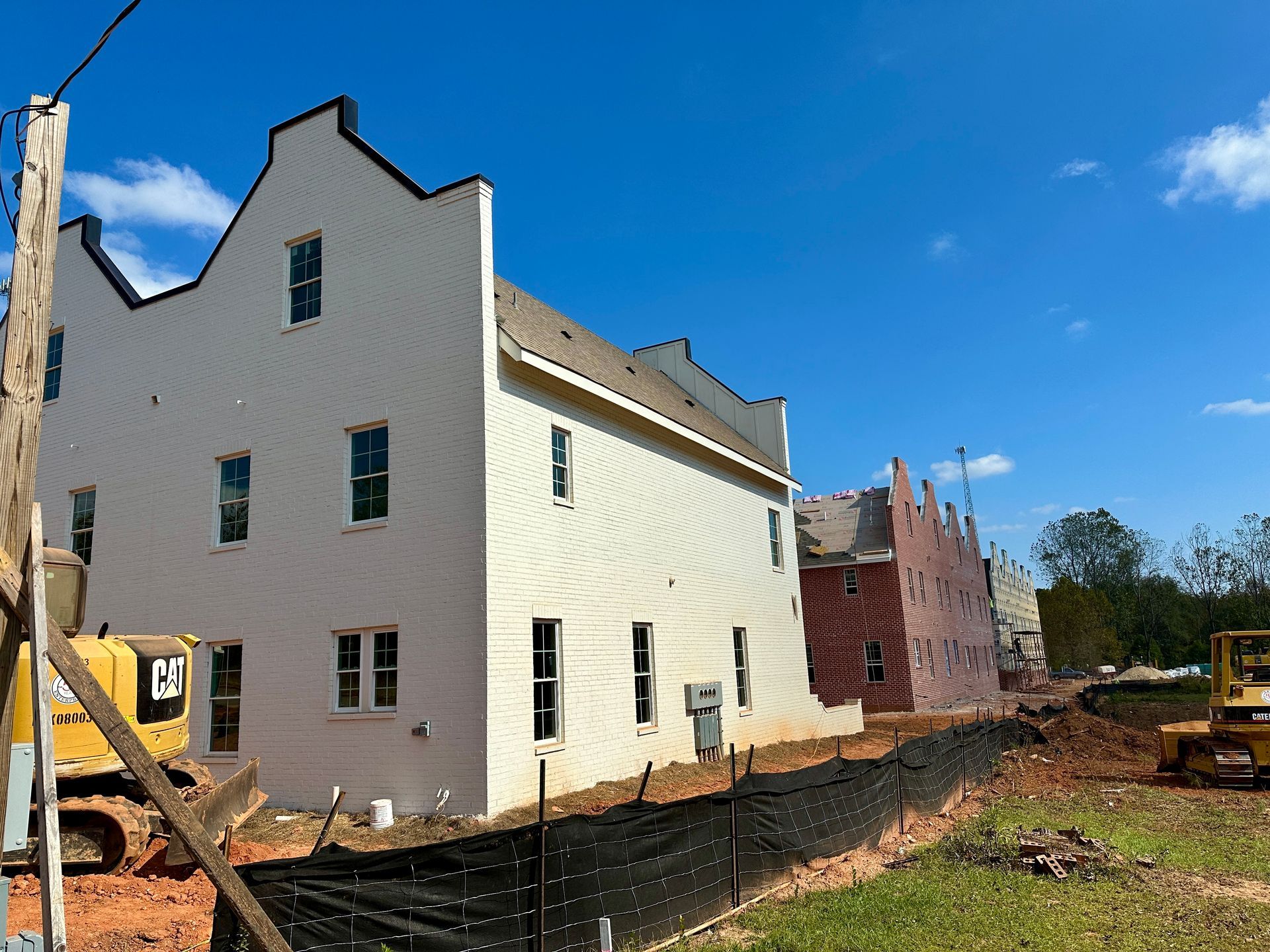 A large white building with a yellow excavator in front of it