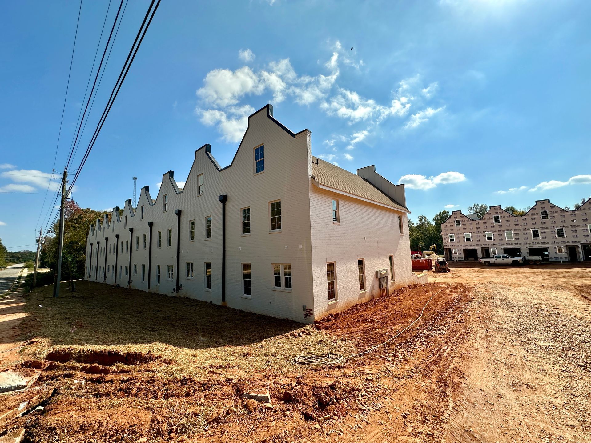 A large white building is sitting in the middle of a dirt road.