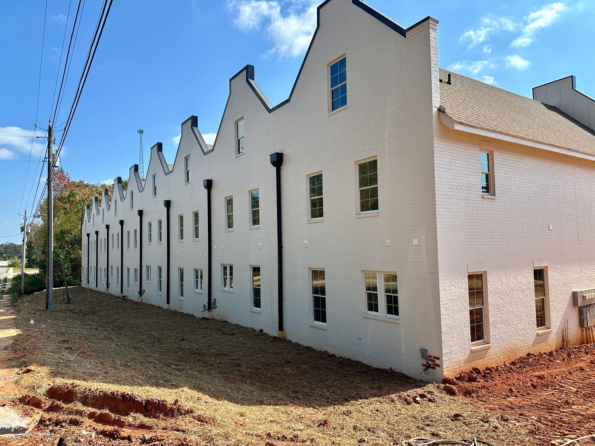 A white building with a lot of windows is sitting on top of a dirt field.