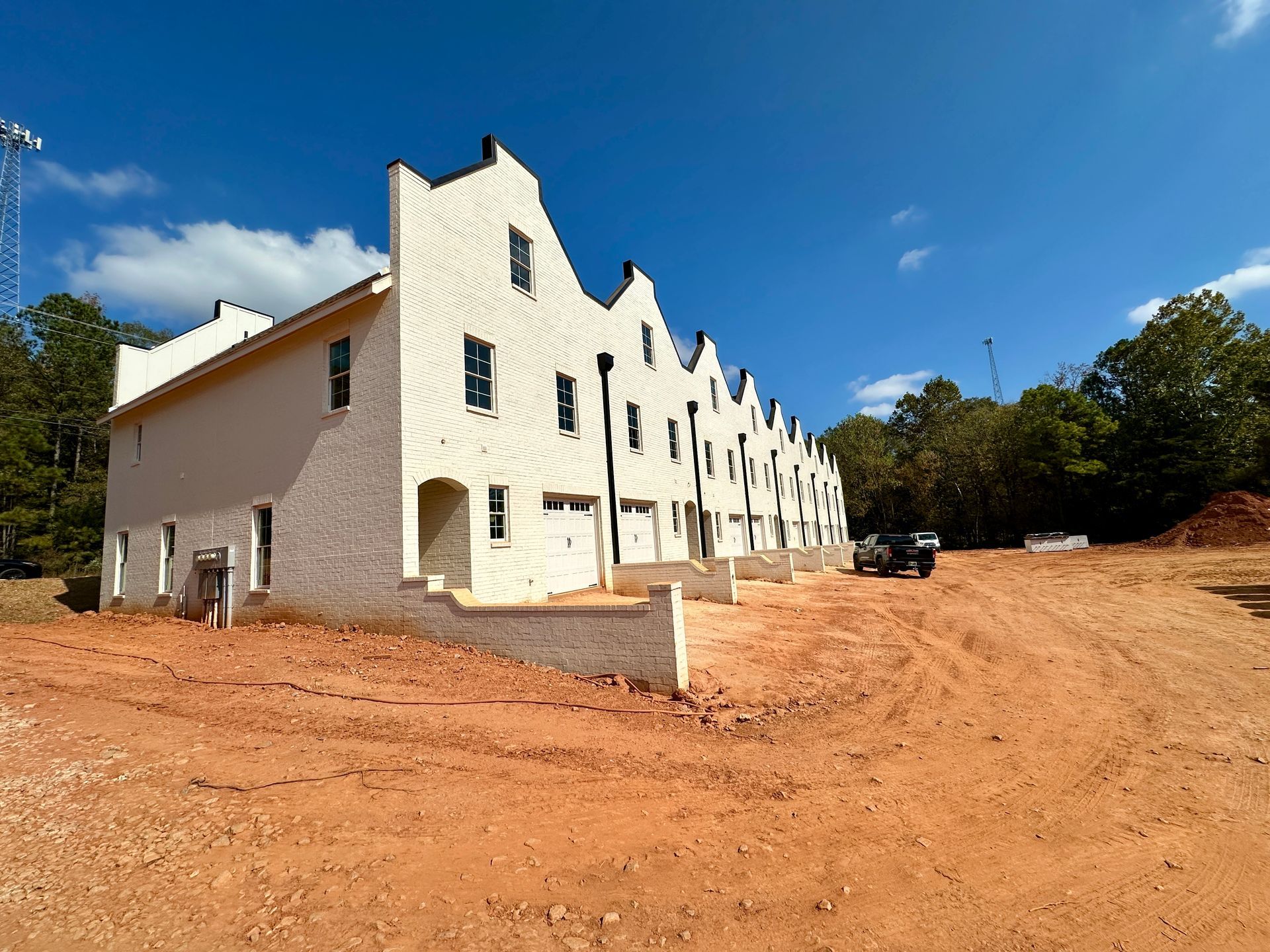 A row of white houses are being built in a dirt field