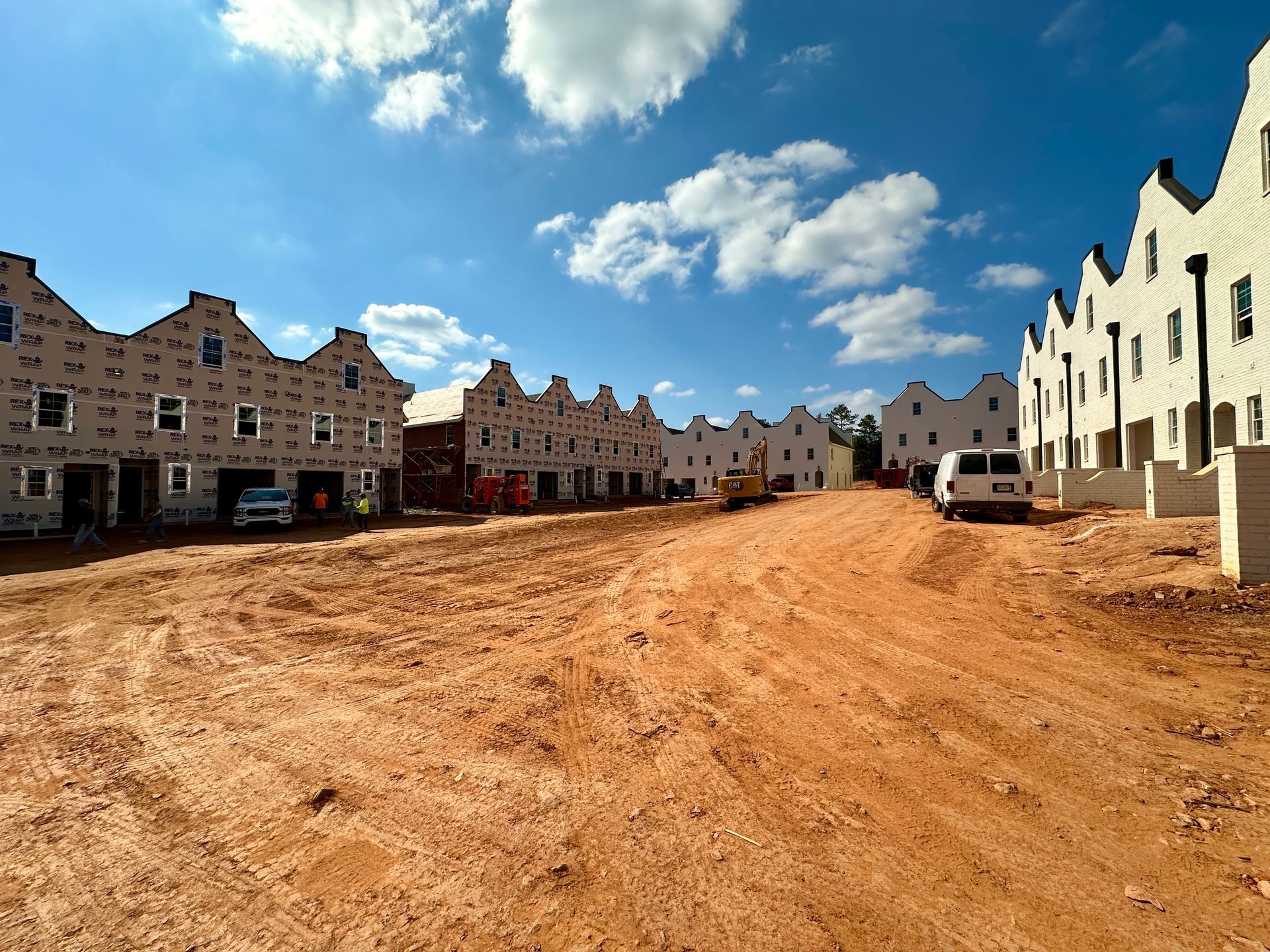 A row of houses are being built on a dirt road