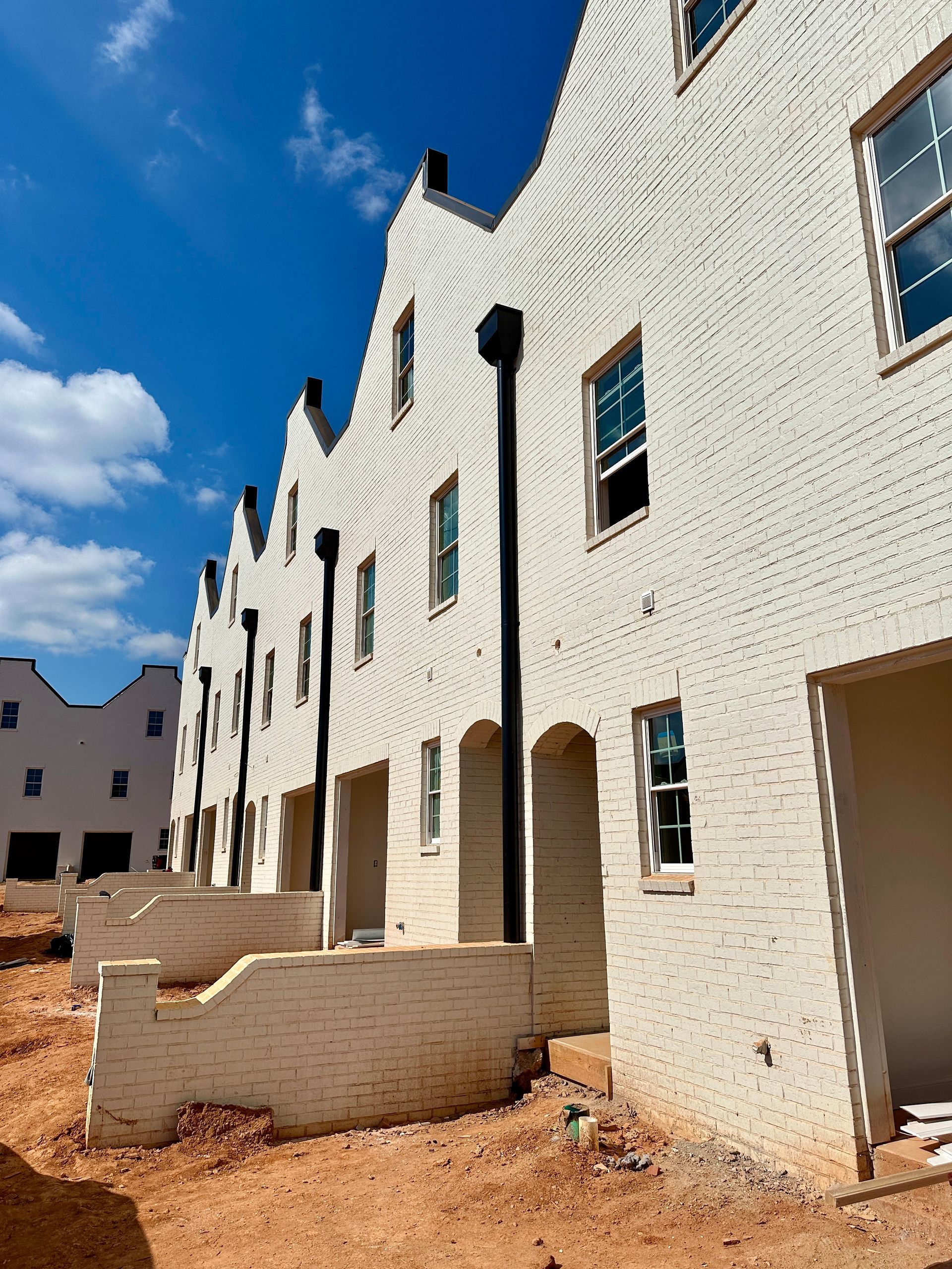 A row of white brick buildings under construction on a sunny day