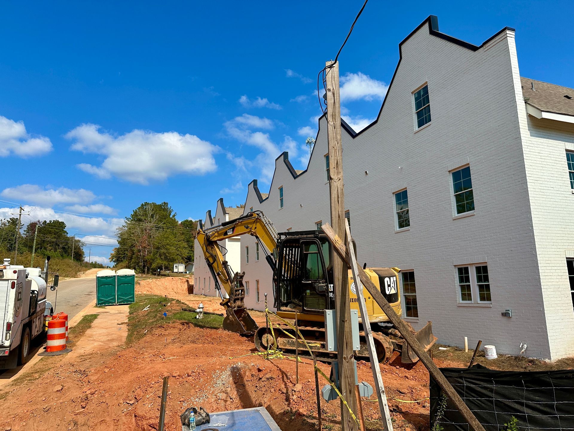 A large white building with a yellow excavator in front of it.