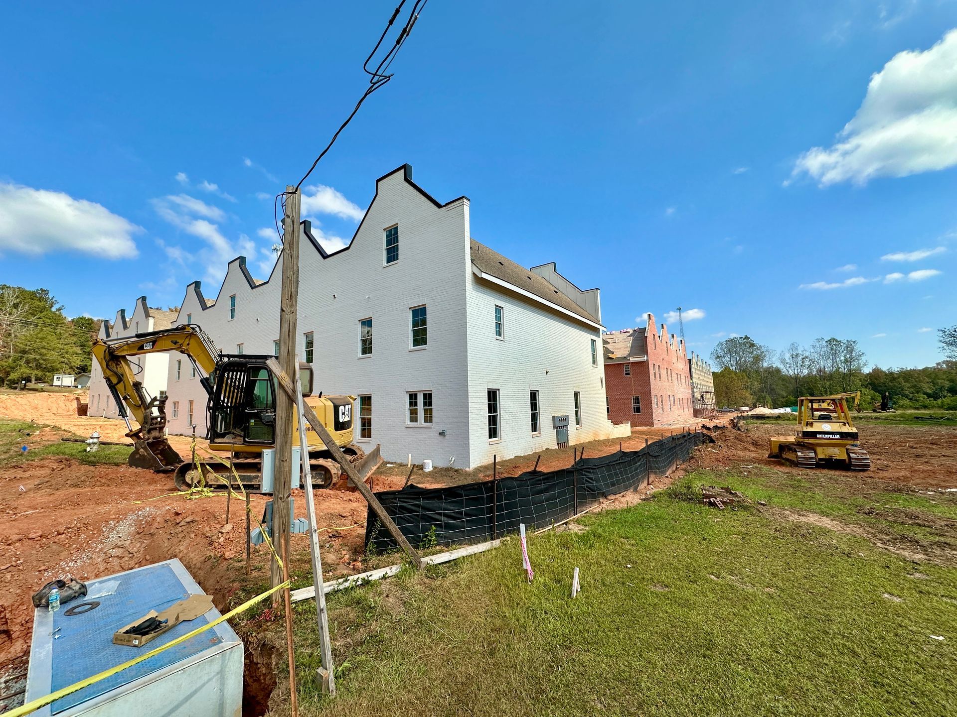 A large white house is being built in a dirt field.