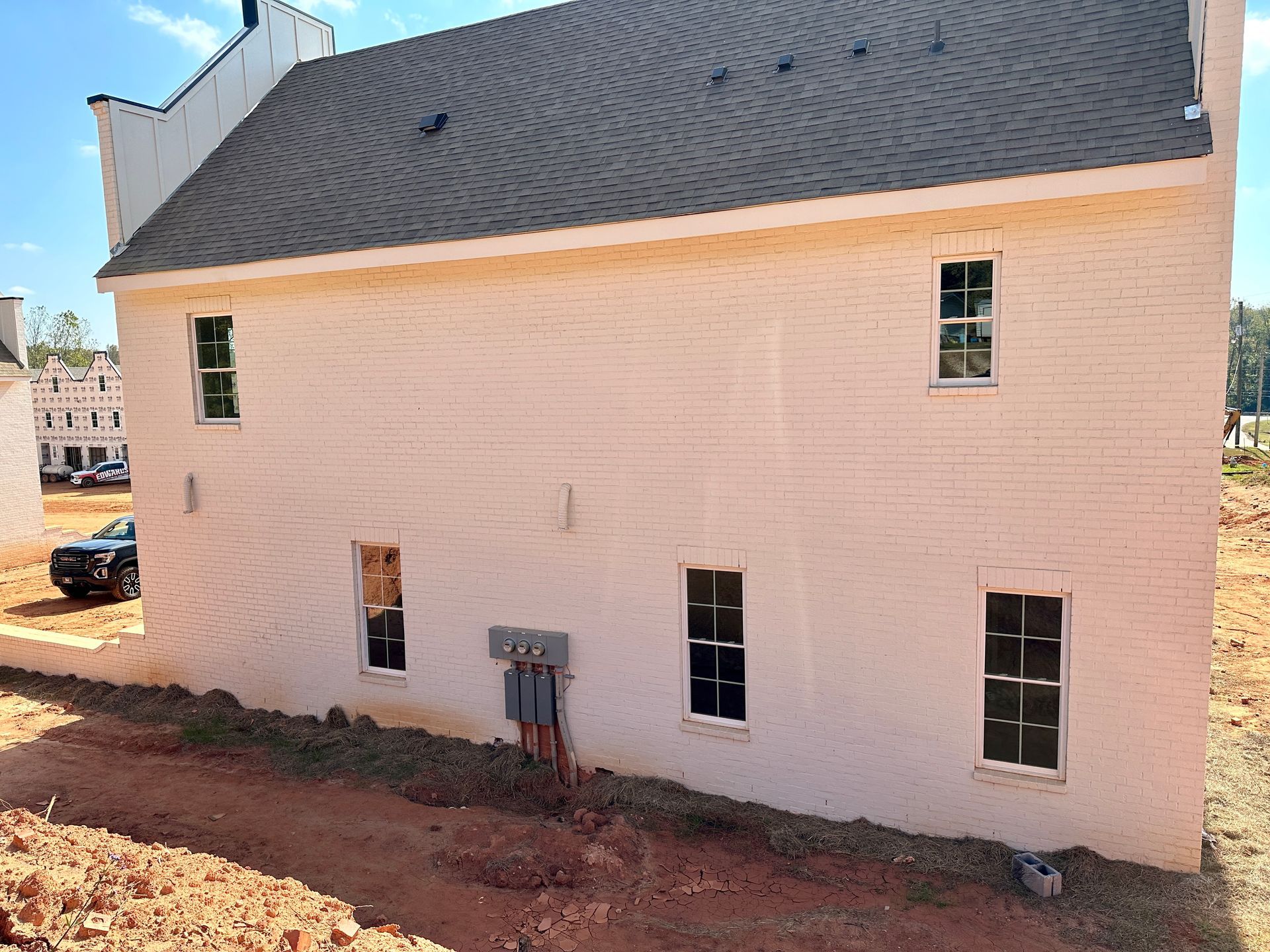 A white house with a black roof is being built in a dirt field.