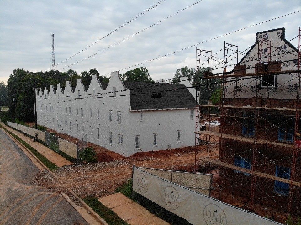 A large brick building under construction with a fence around it.