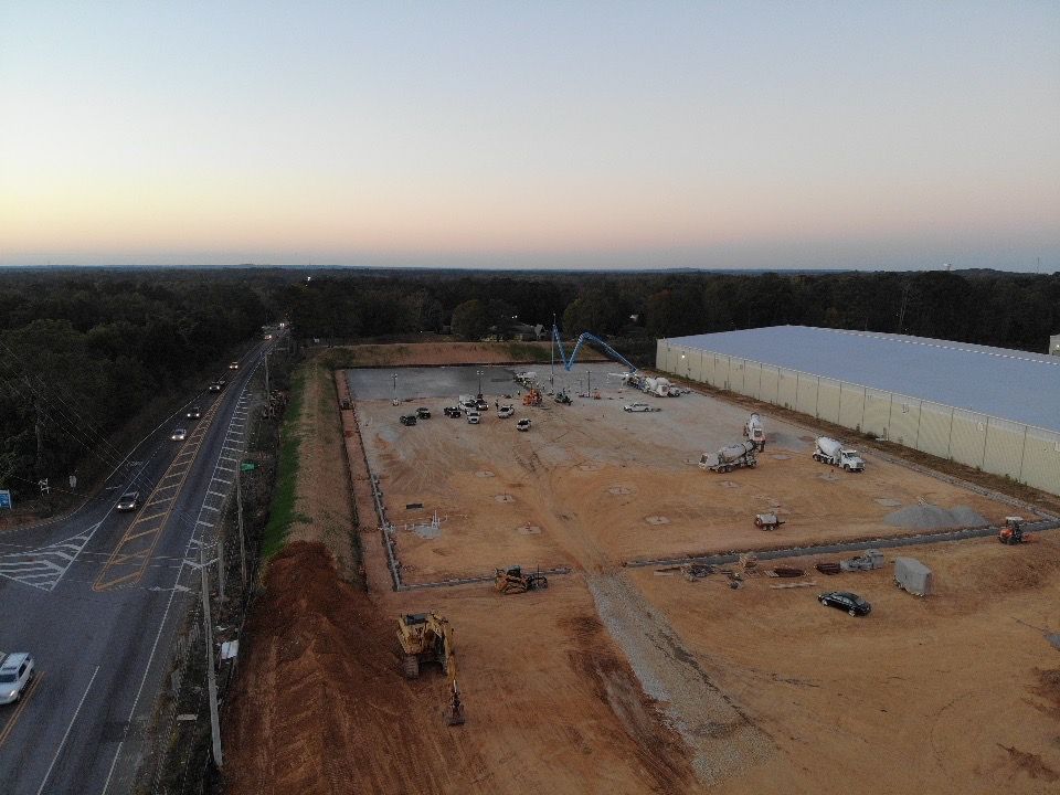 An aerial view of a construction site with a large building in the background.