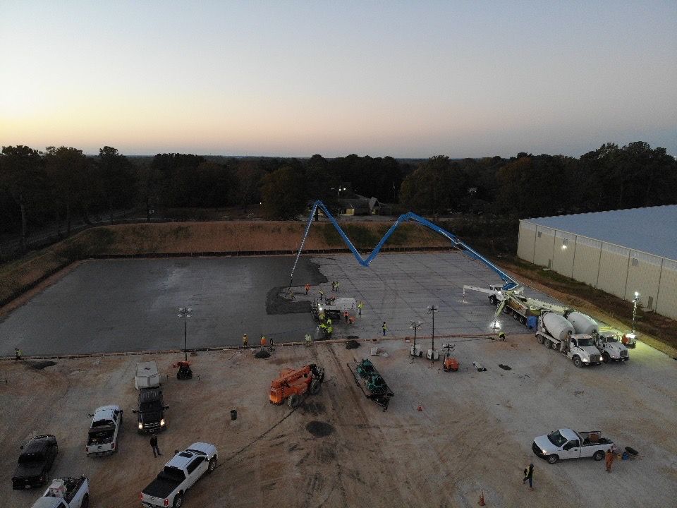 An aerial view of a construction site with trucks and a concrete pump.