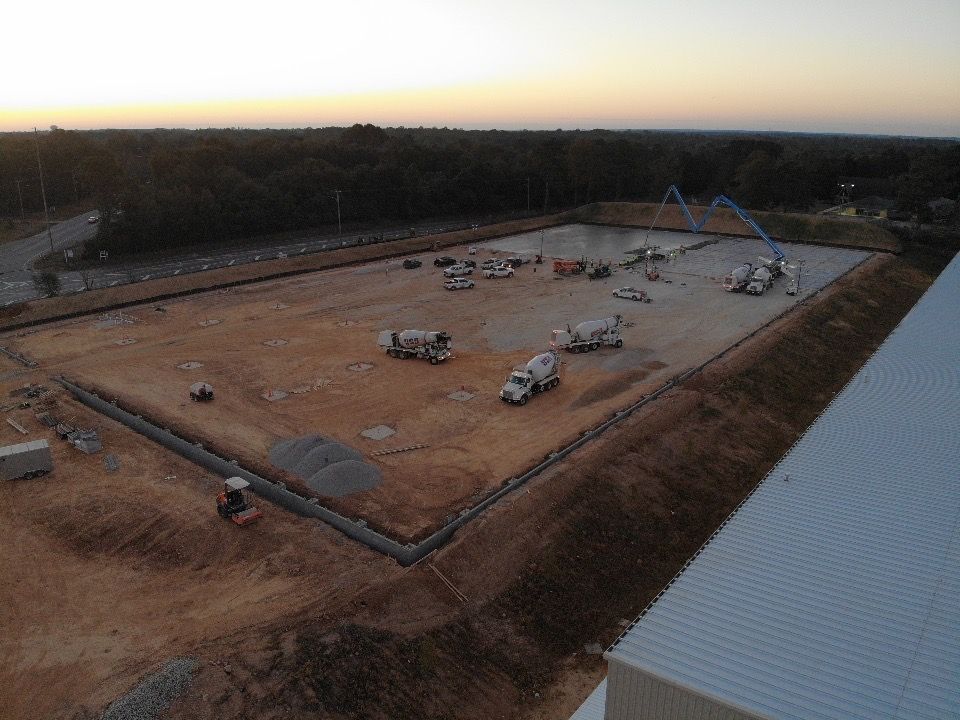 An aerial view of a construction site with trucks pouring concrete.