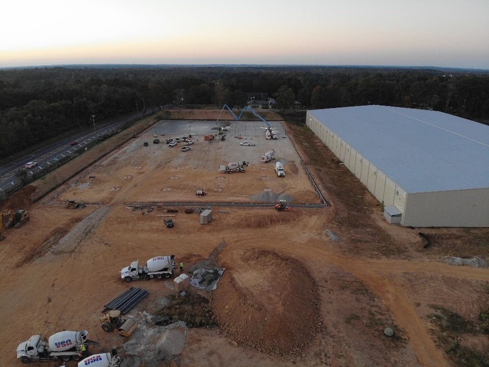 An aerial view of a construction site with a large building in the background.
