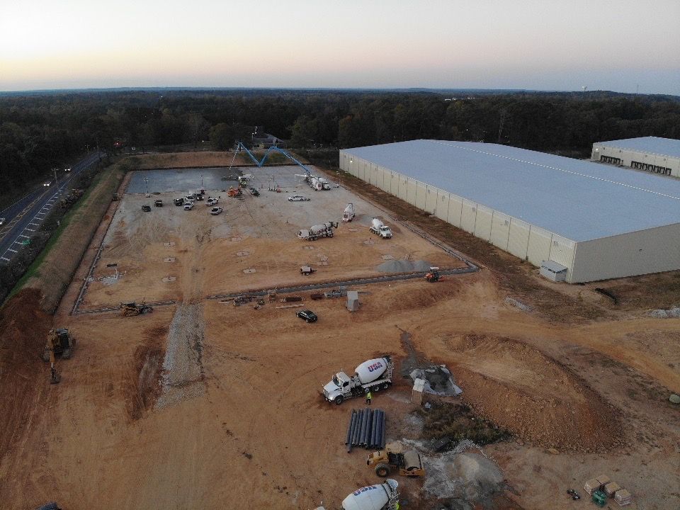 An aerial view of a construction site with a large building in the background.
