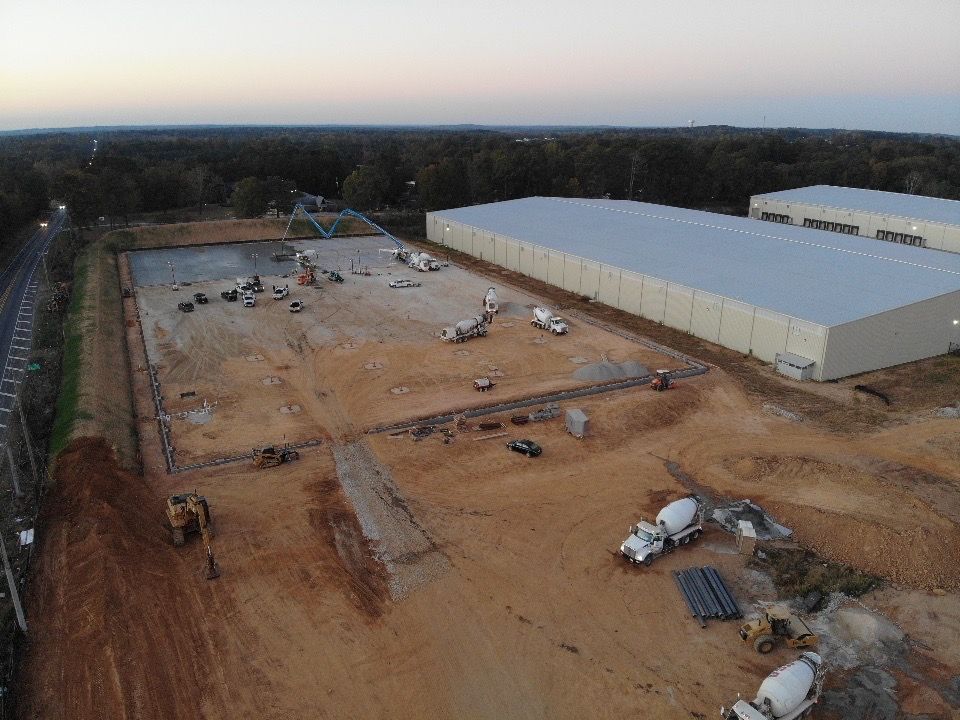 An aerial view of a construction site with a large building in the background.