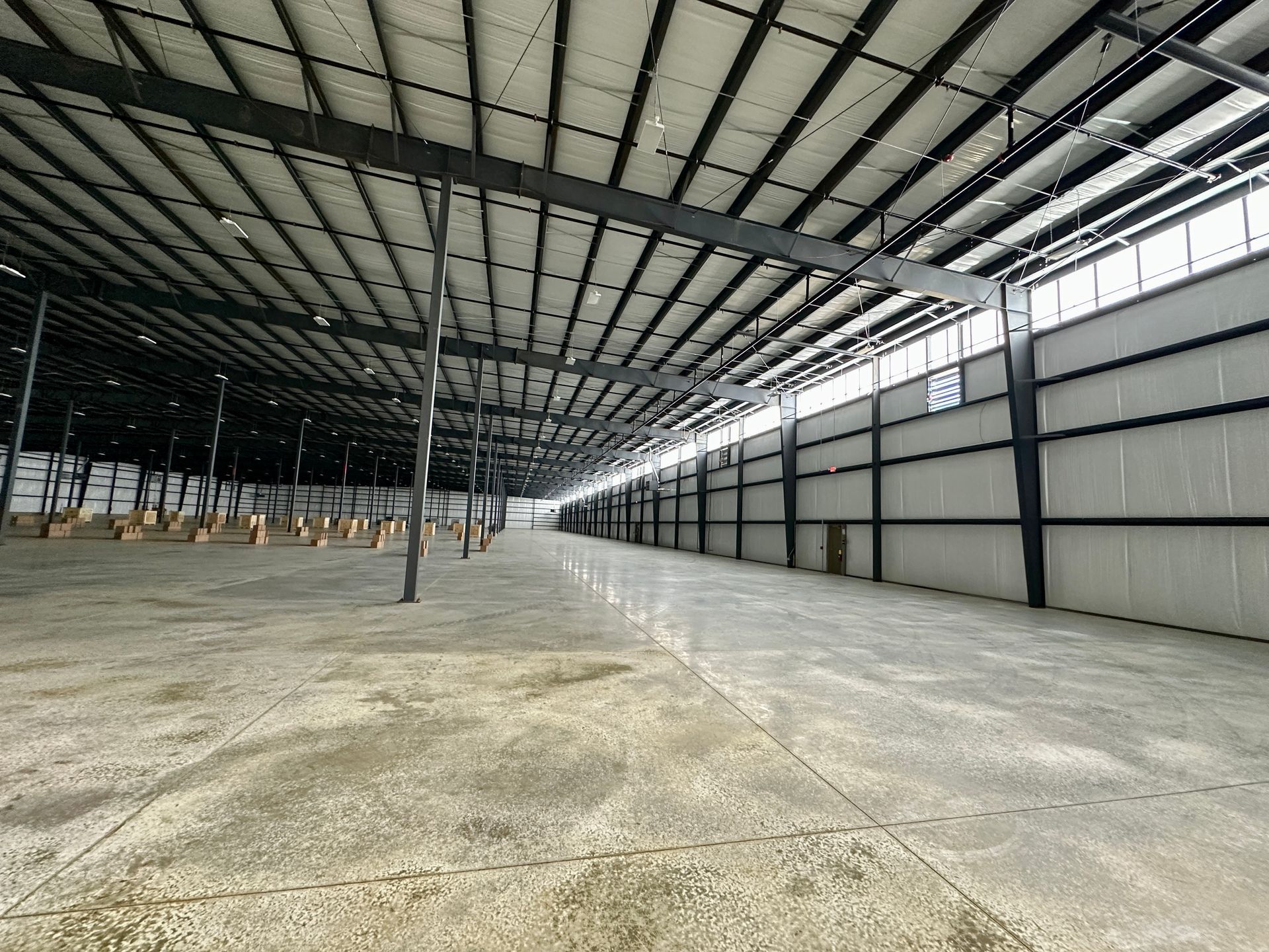 A large empty warehouse with a lot of windows and a concrete floor.