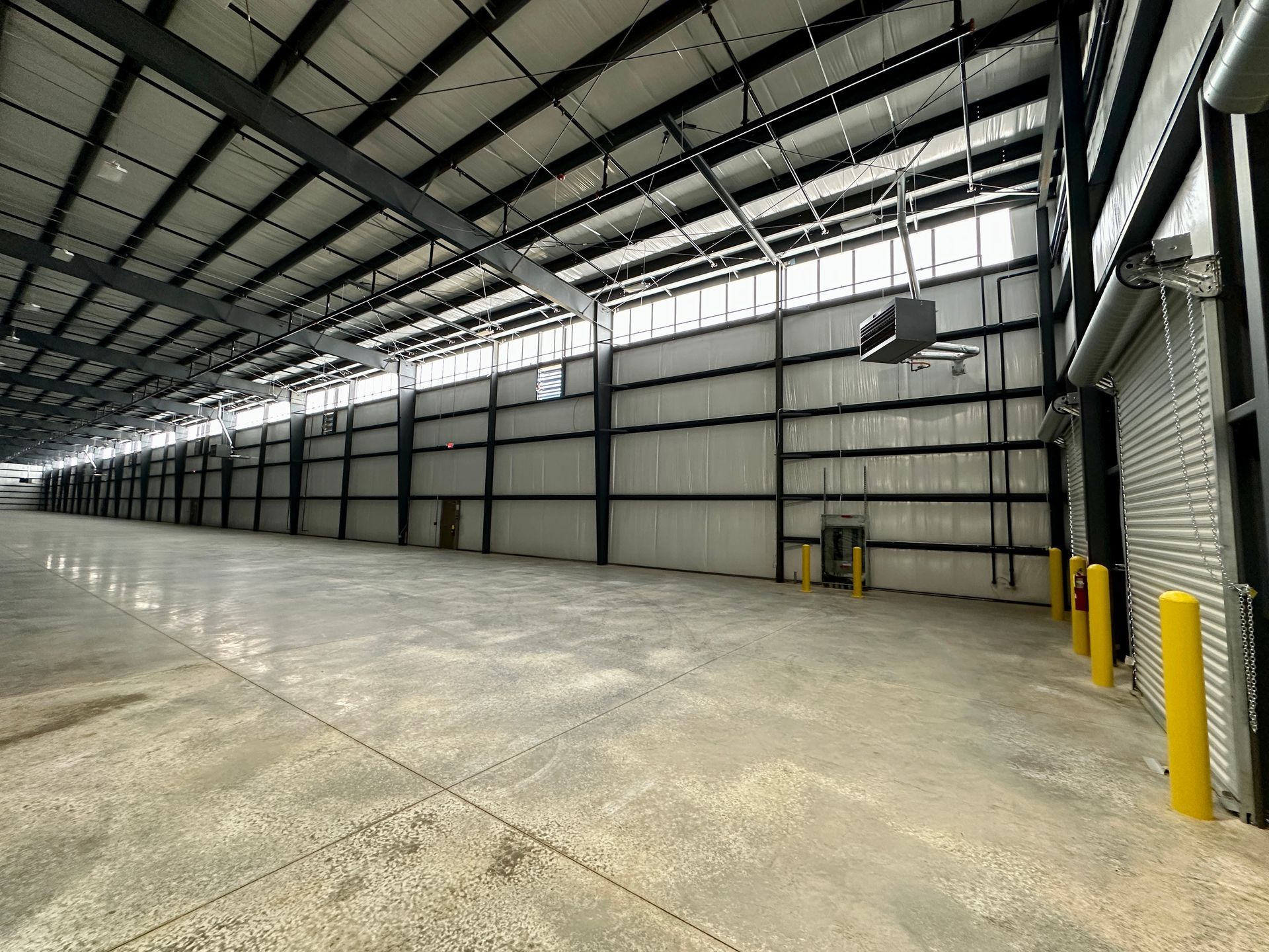 An empty warehouse with a lot of windows and a concrete floor.