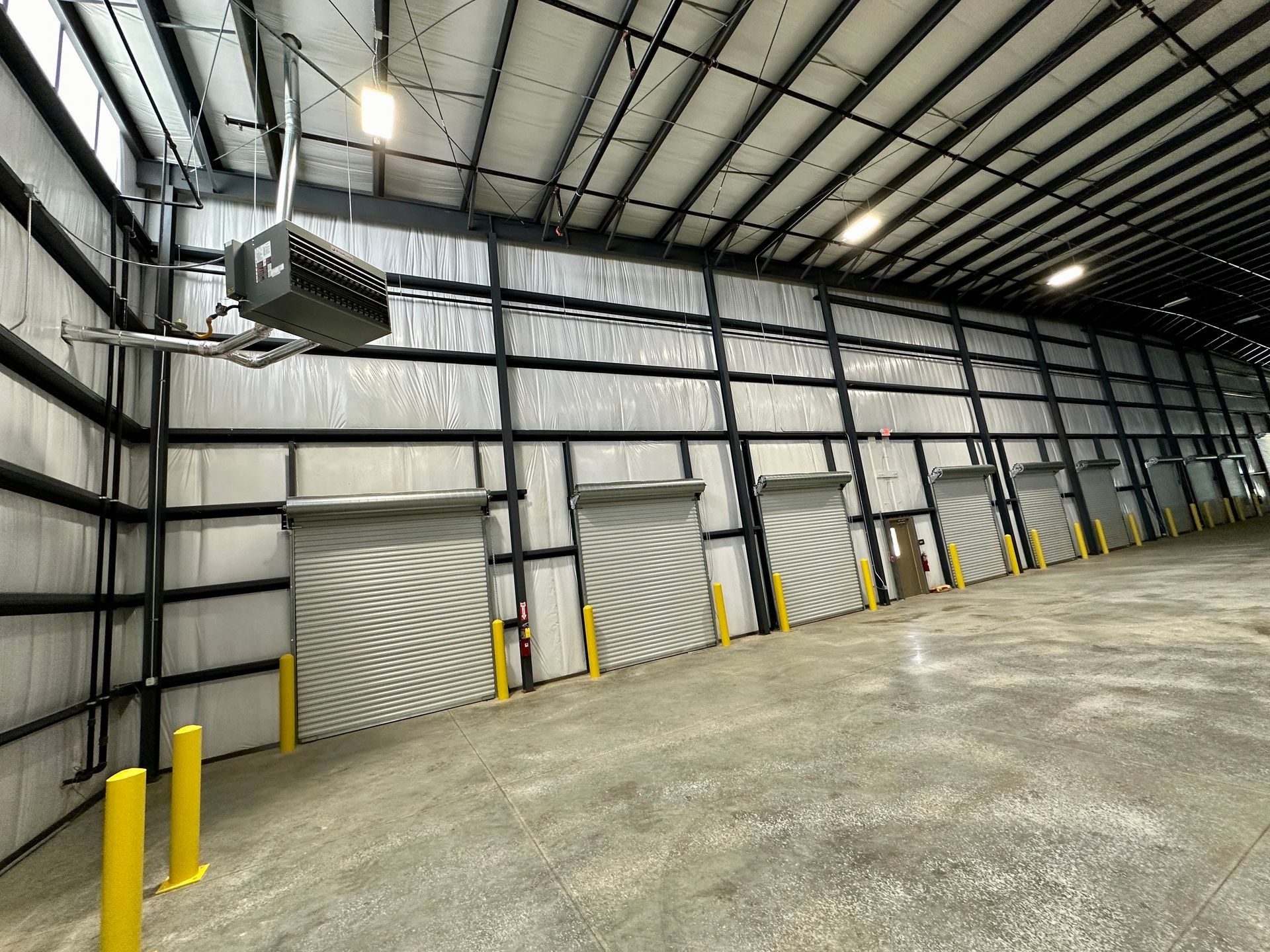 A large warehouse with a lot of doors and poles.