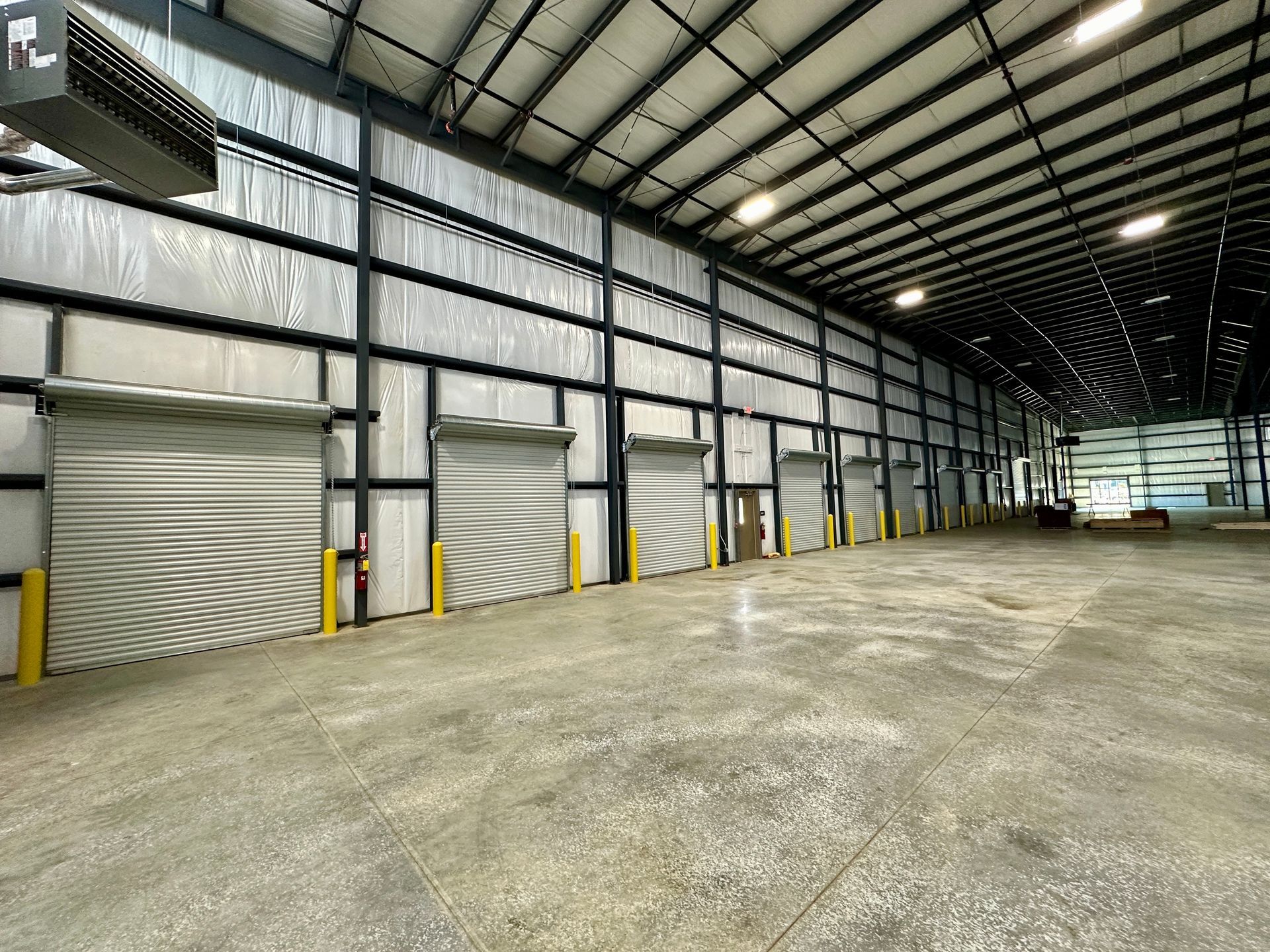 A large warehouse with lots of roller doors and a ceiling fan.