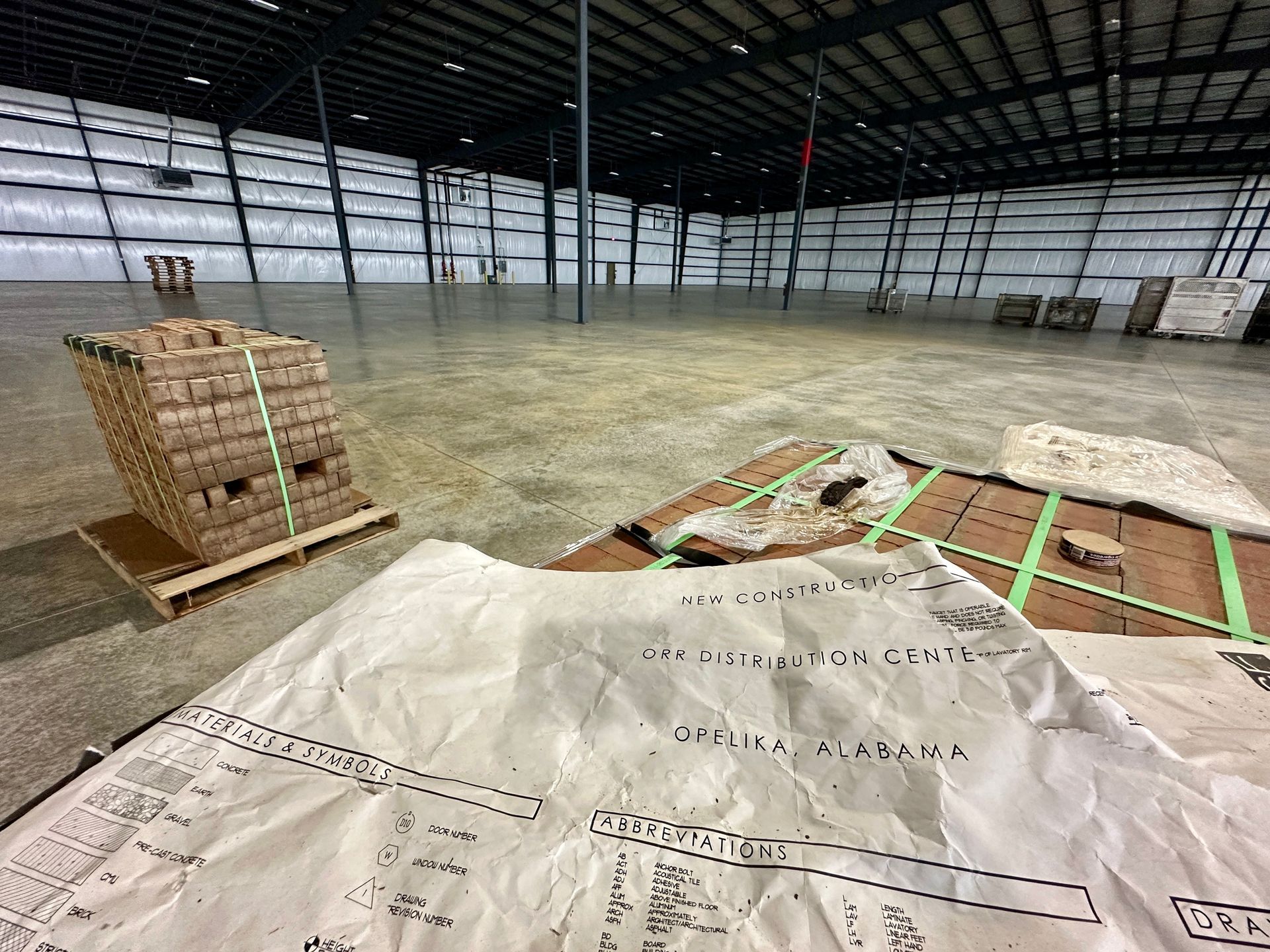 A large warehouse with a lot of boxes and papers on the floor.