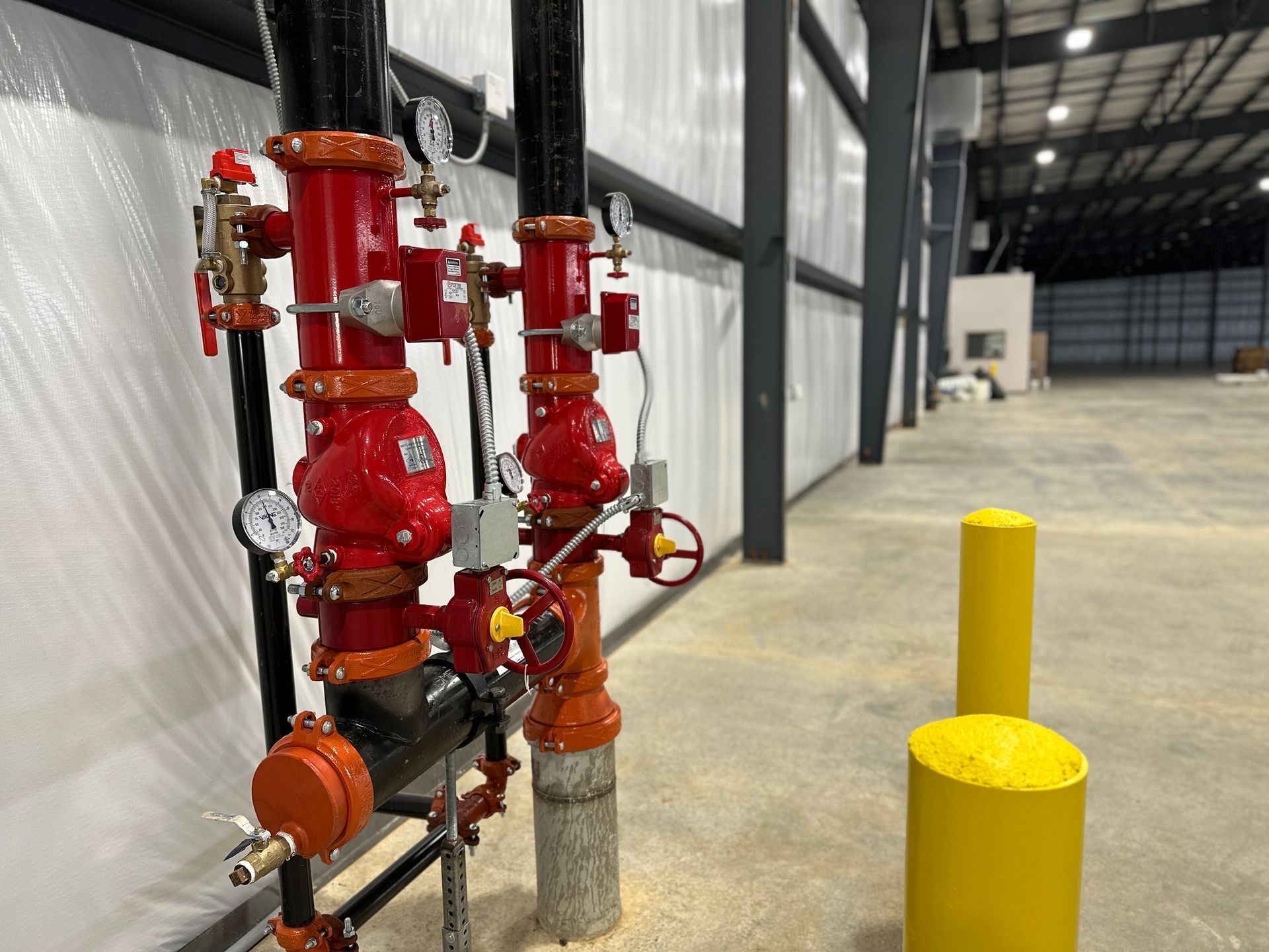 A warehouse with a lot of red pipes and yellow poles.