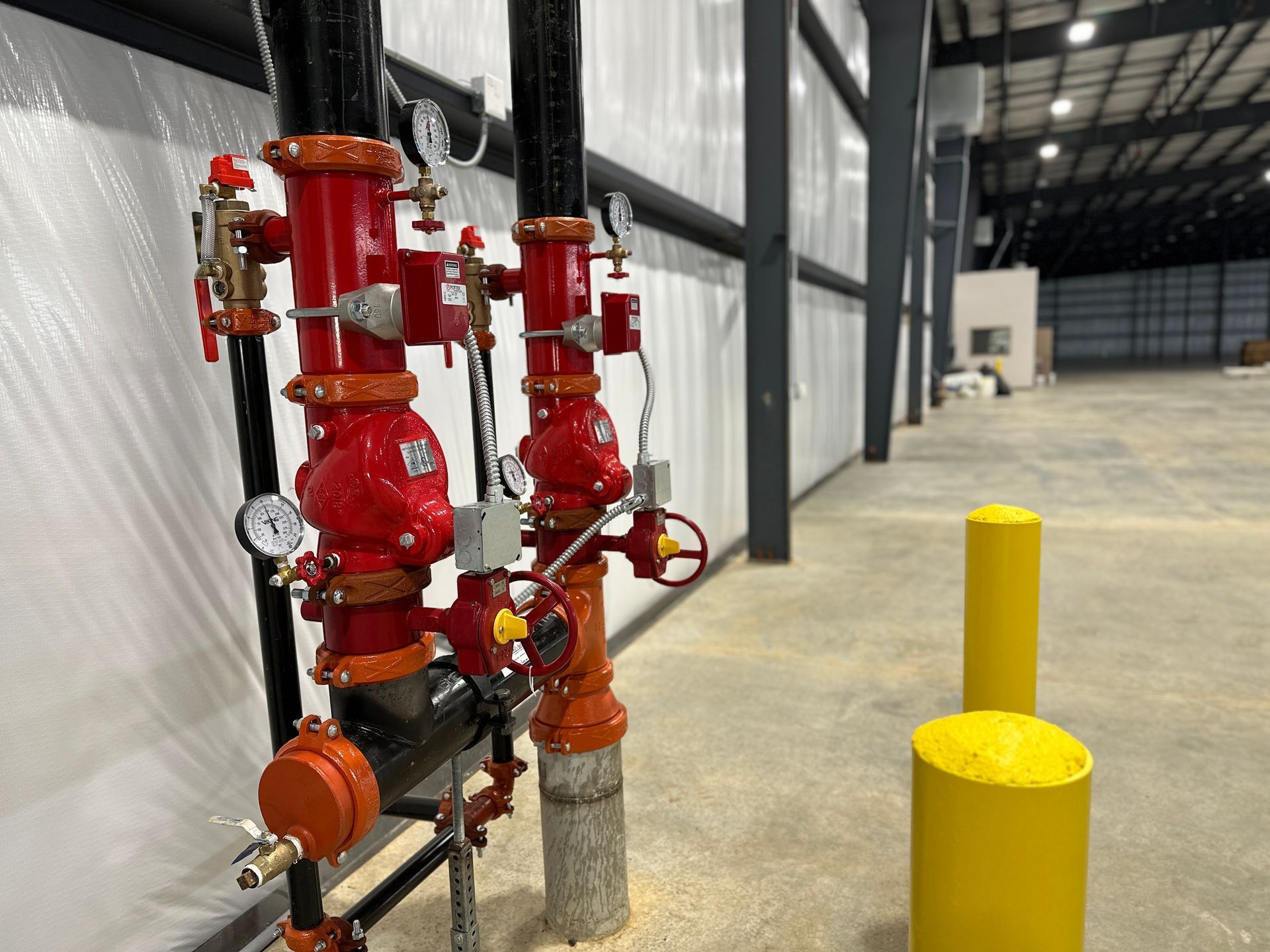 A warehouse with a lot of red pipes and yellow poles.