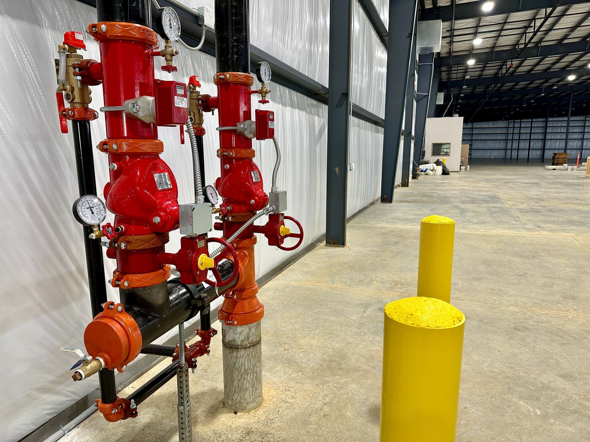 A warehouse with a lot of red pipes and yellow poles.