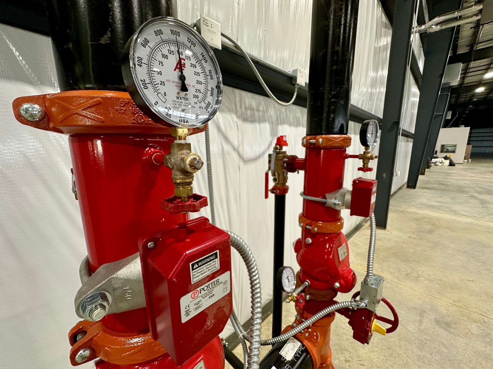 A red fire hydrant with a pressure gauge attached to it.