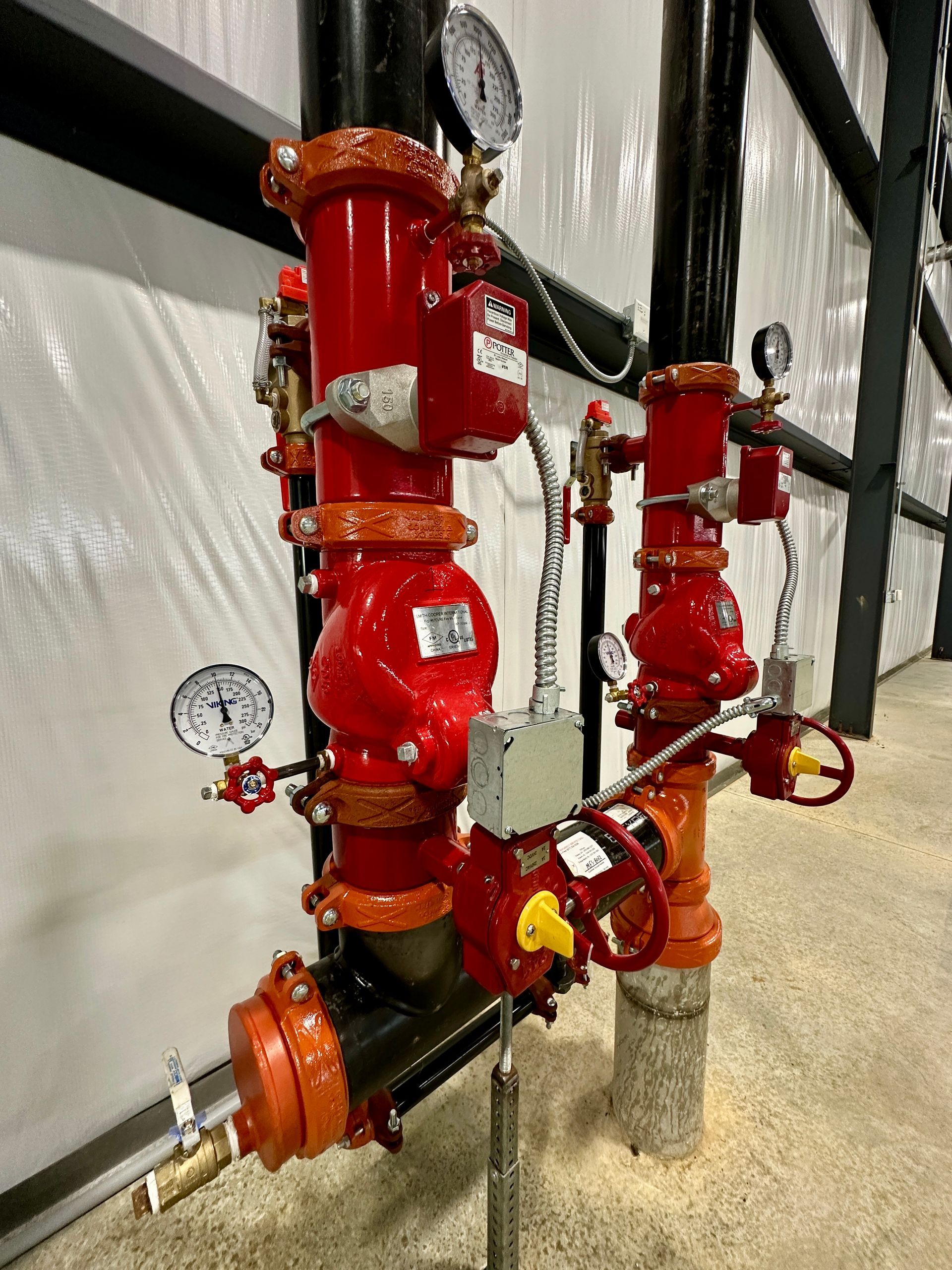 A bunch of red pipes and valves are sitting next to each other in a room.