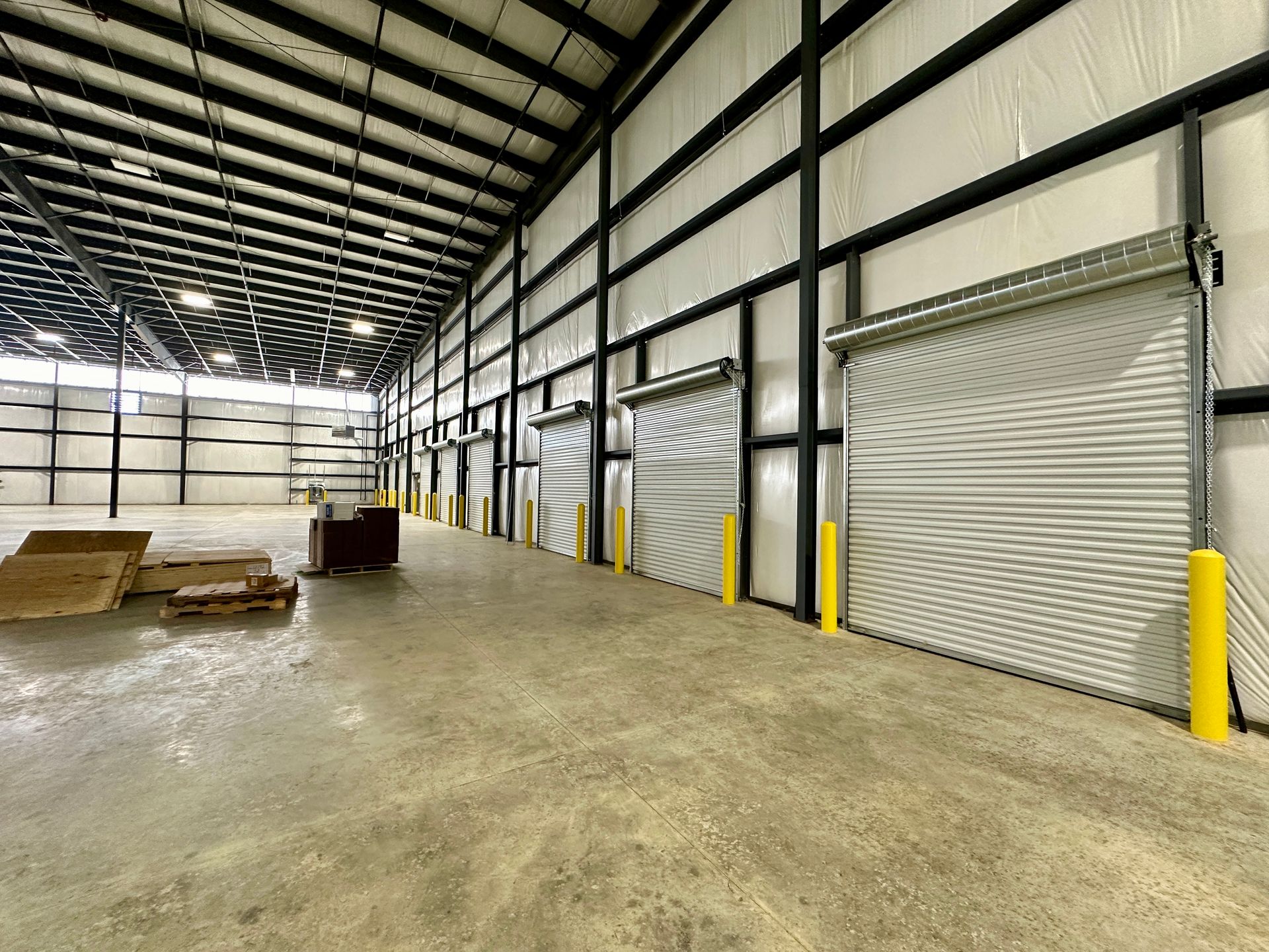 A large warehouse with a lot of doors and boxes on the floor.