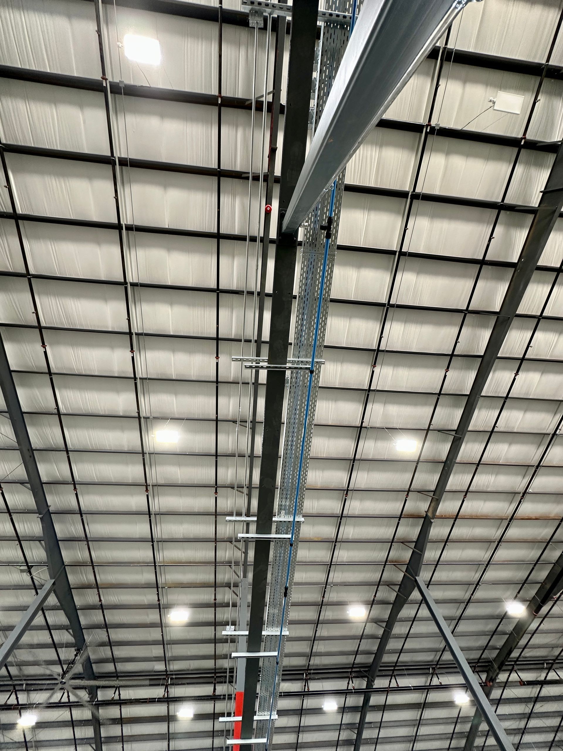 The ceiling of a large building with a lot of wires hanging from it.