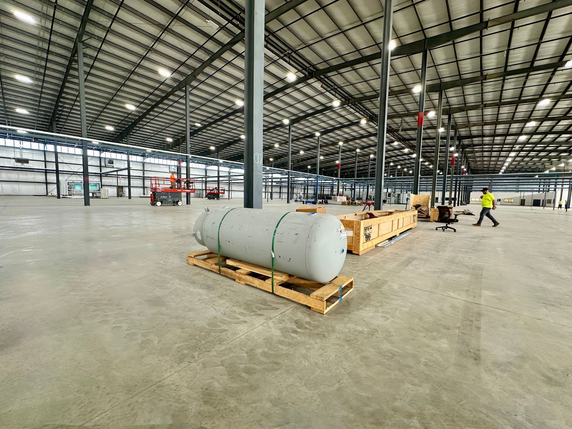 A large tank is sitting on a wooden pallet in a large warehouse.