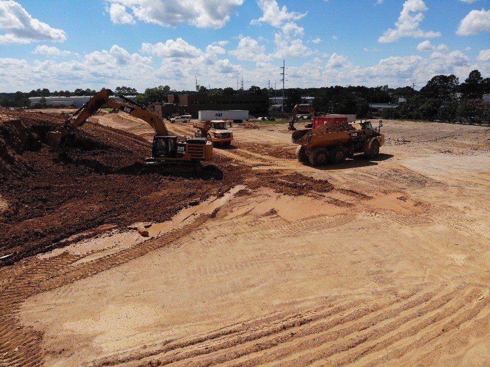 A group of construction vehicles are working on a dirt road.