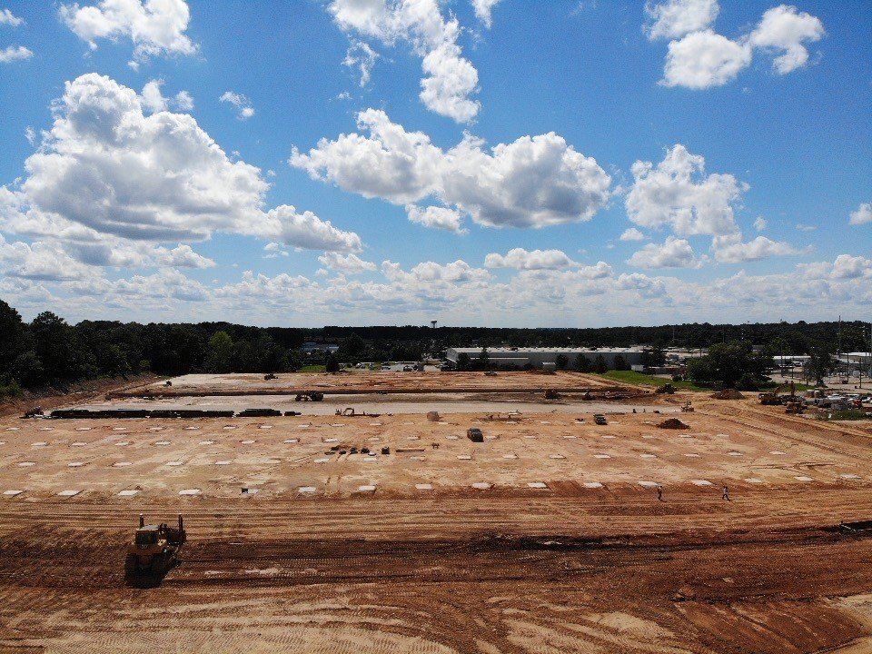 An aerial view of a construction site with a blue sky and clouds