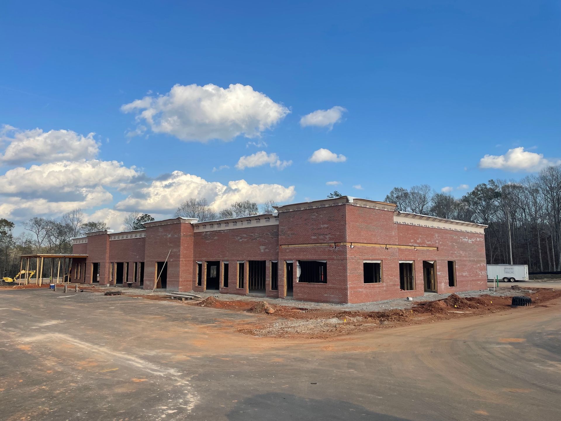 A large brick building is being built in the middle of a dirt field.