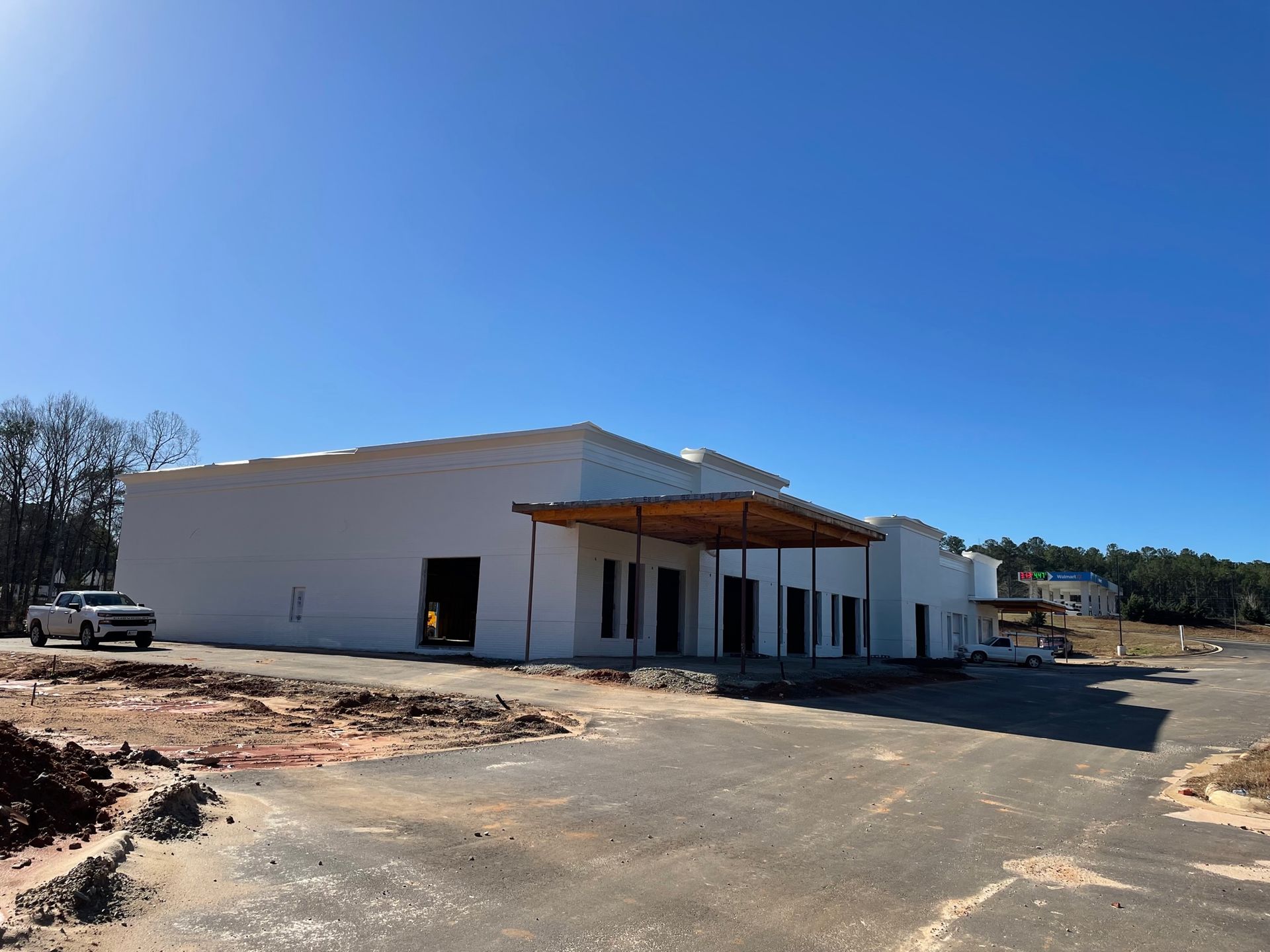 A white truck is parked in front of a building under construction.